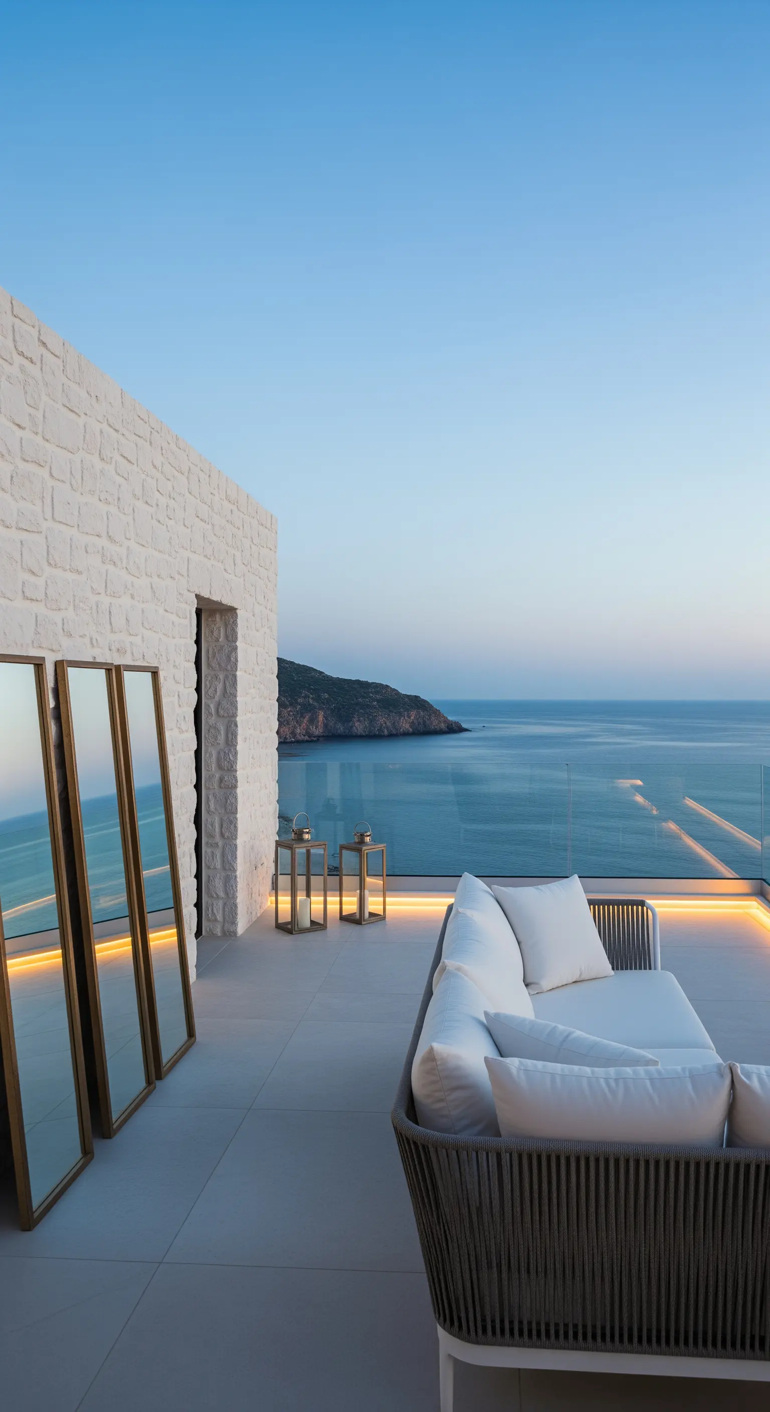 Terrazza vista mare con divano in tessuto intrecciato e tre specchi dorati appoggiati al muro