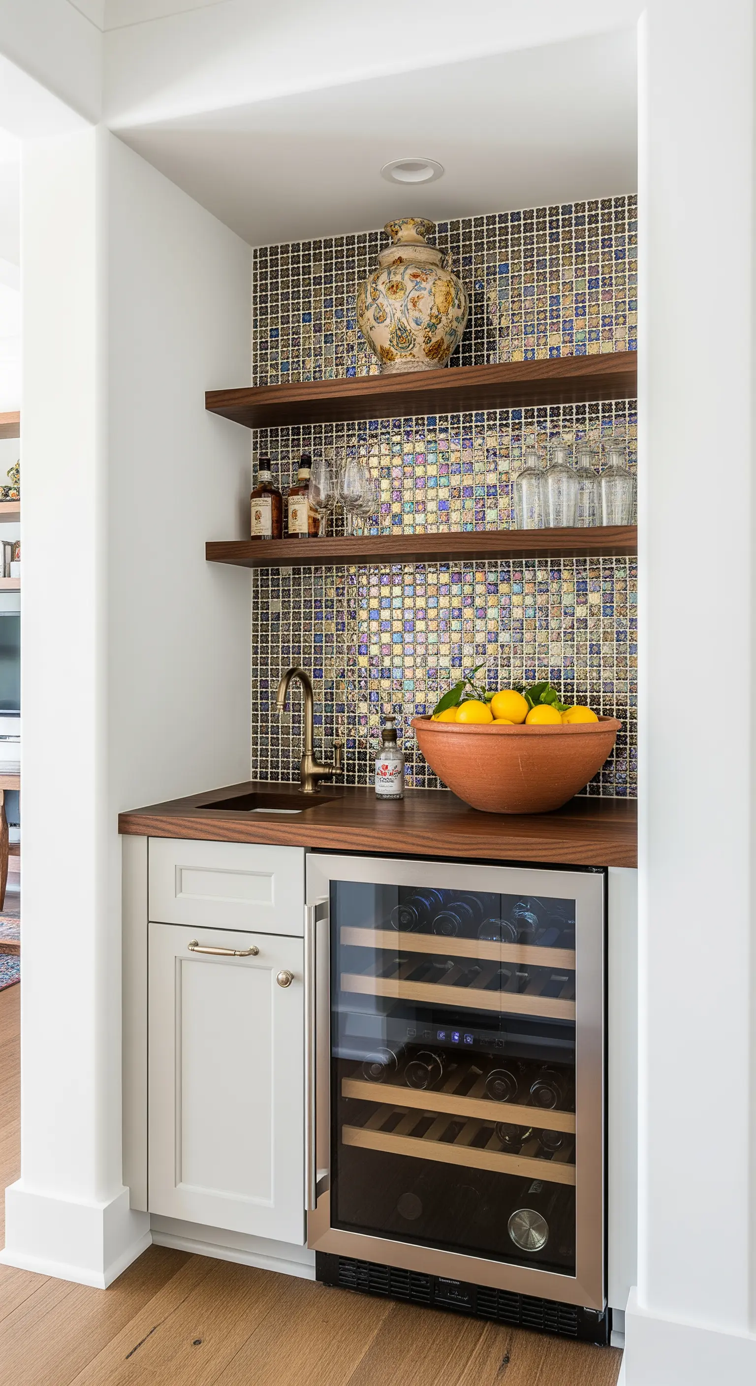 Angolo bar con paraschizzi in mosaico cangiante, mensole in legno e piccola cantinetta per vini.