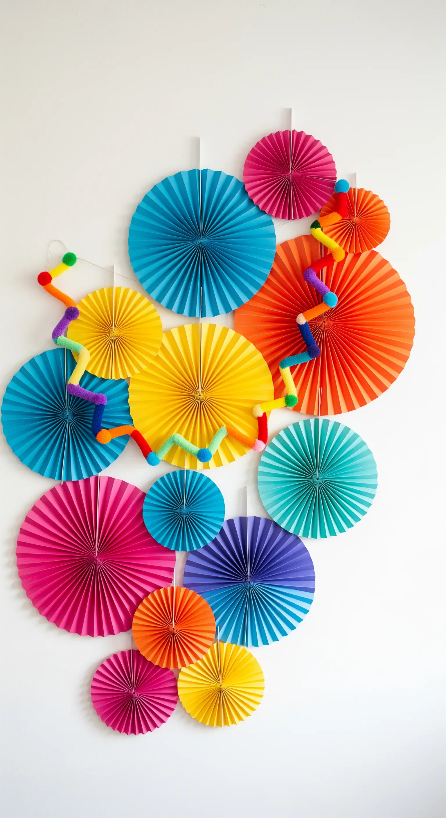 Composizione murale con ventagli di carta di varie dimensioni e colori vivaci.