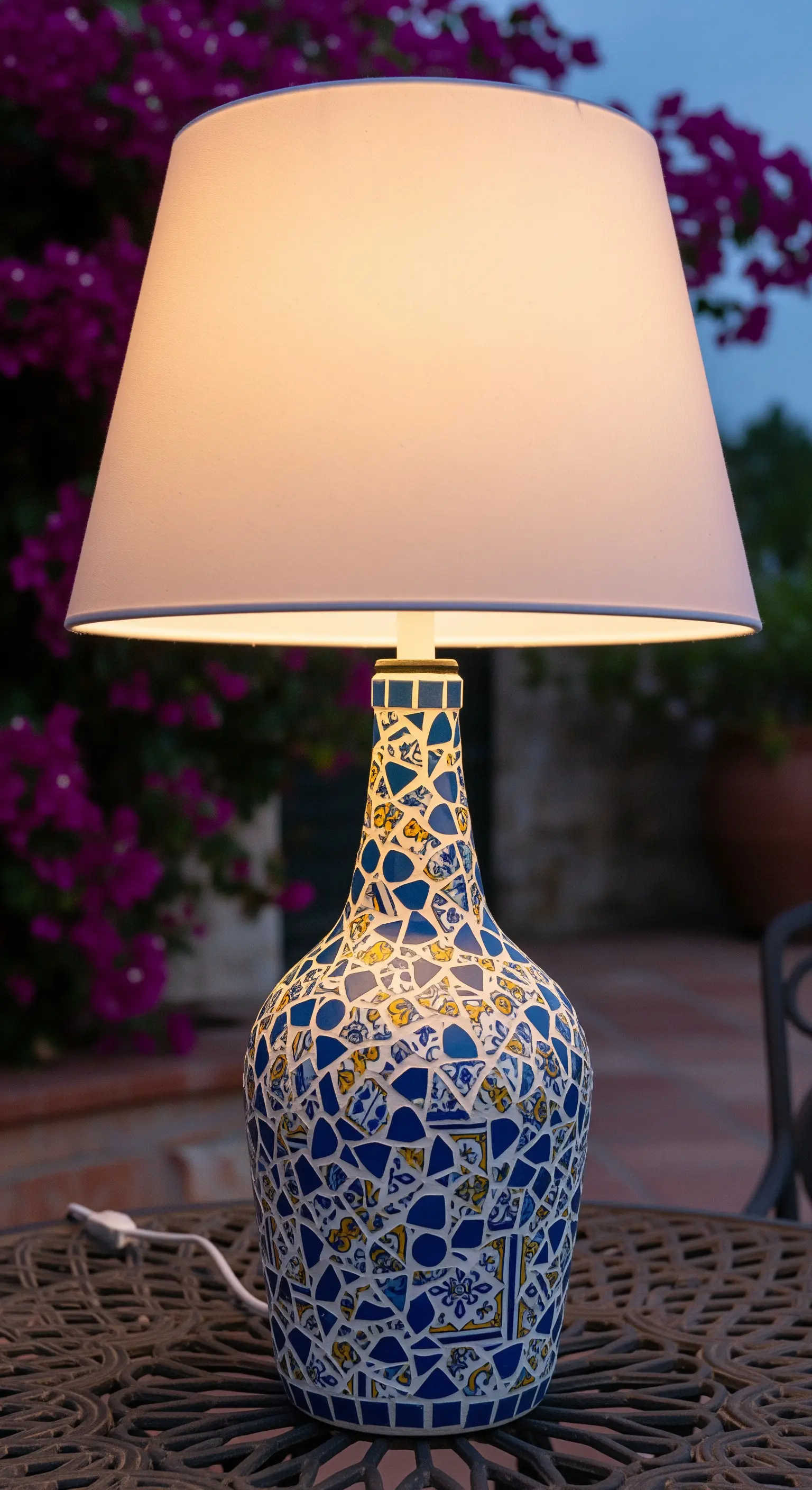 Base per lampada decorata con un mosaico di piastrelle blu, gialle e bianche.