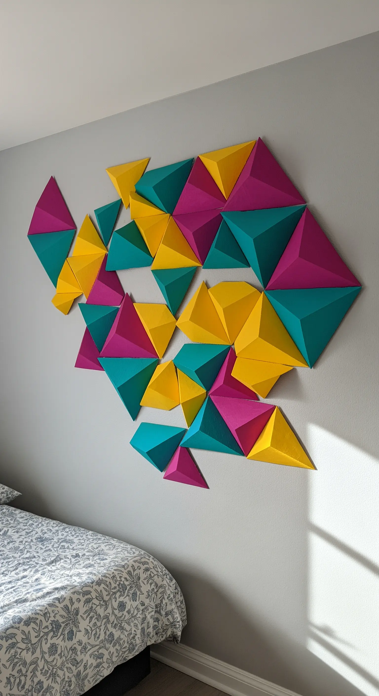 Decorazione murale 3D con piramidi di carta colorata magenta, gialla e verde acqua.