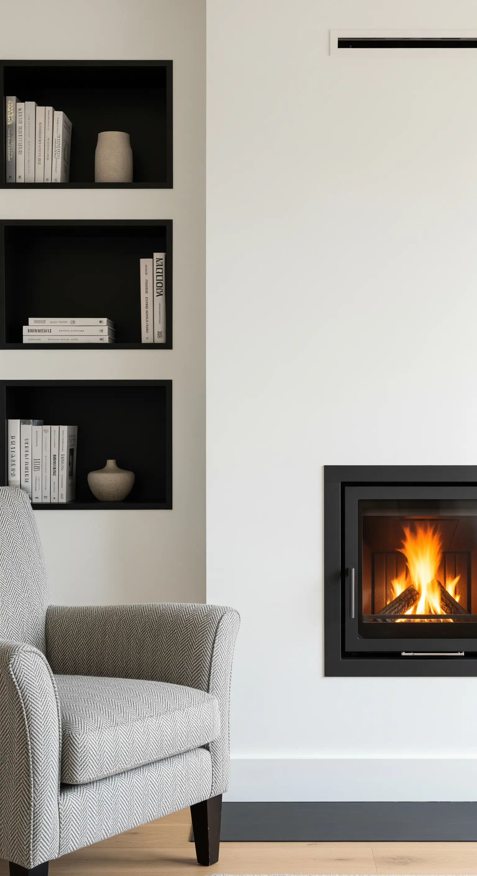 Camino moderno con nicchie nere a incasso e poltrona in tessuto grigio.