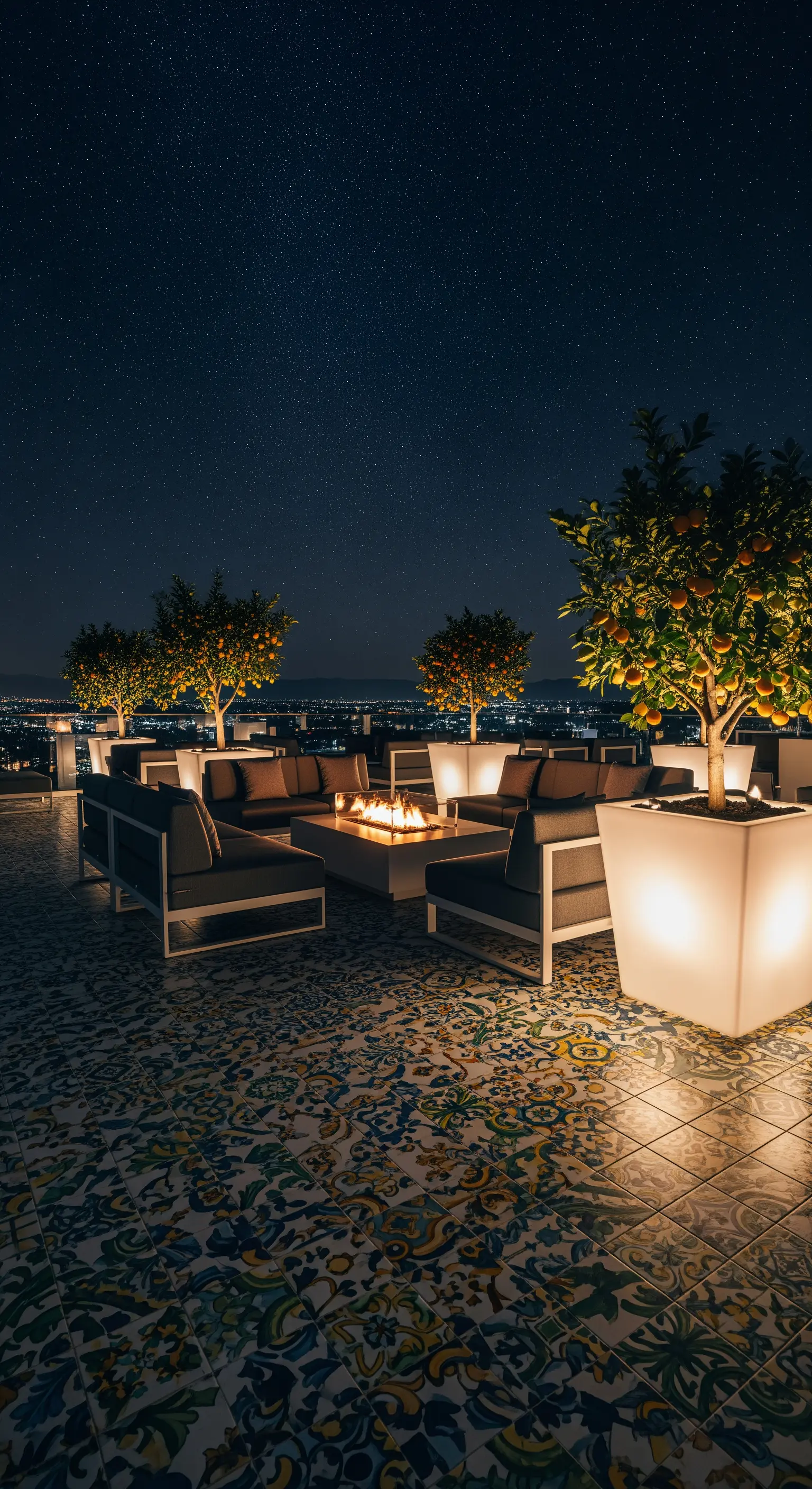 Rooftop di notte con divani moderni, un braciere e grandi vasi luminosi con alberi di arancio.