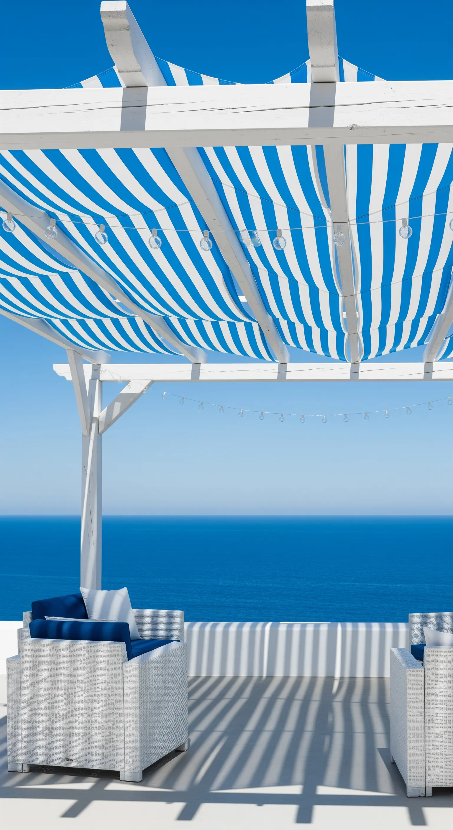 Pergolato bianco con teli a righe blu e bianche che creano ombra.