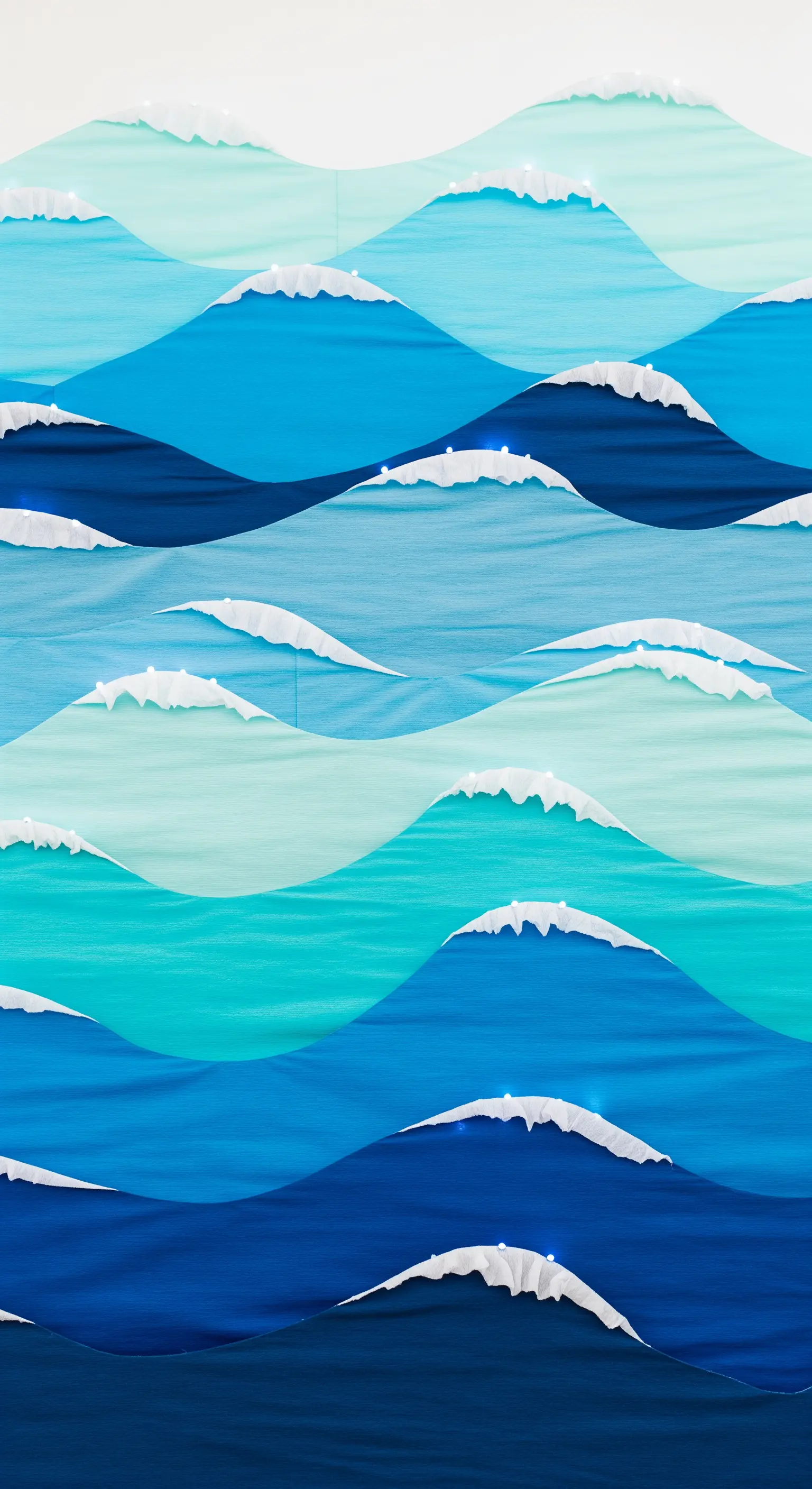 Fondale che riproduce le onde del mare con strati di carta crespa blu e bianca.
