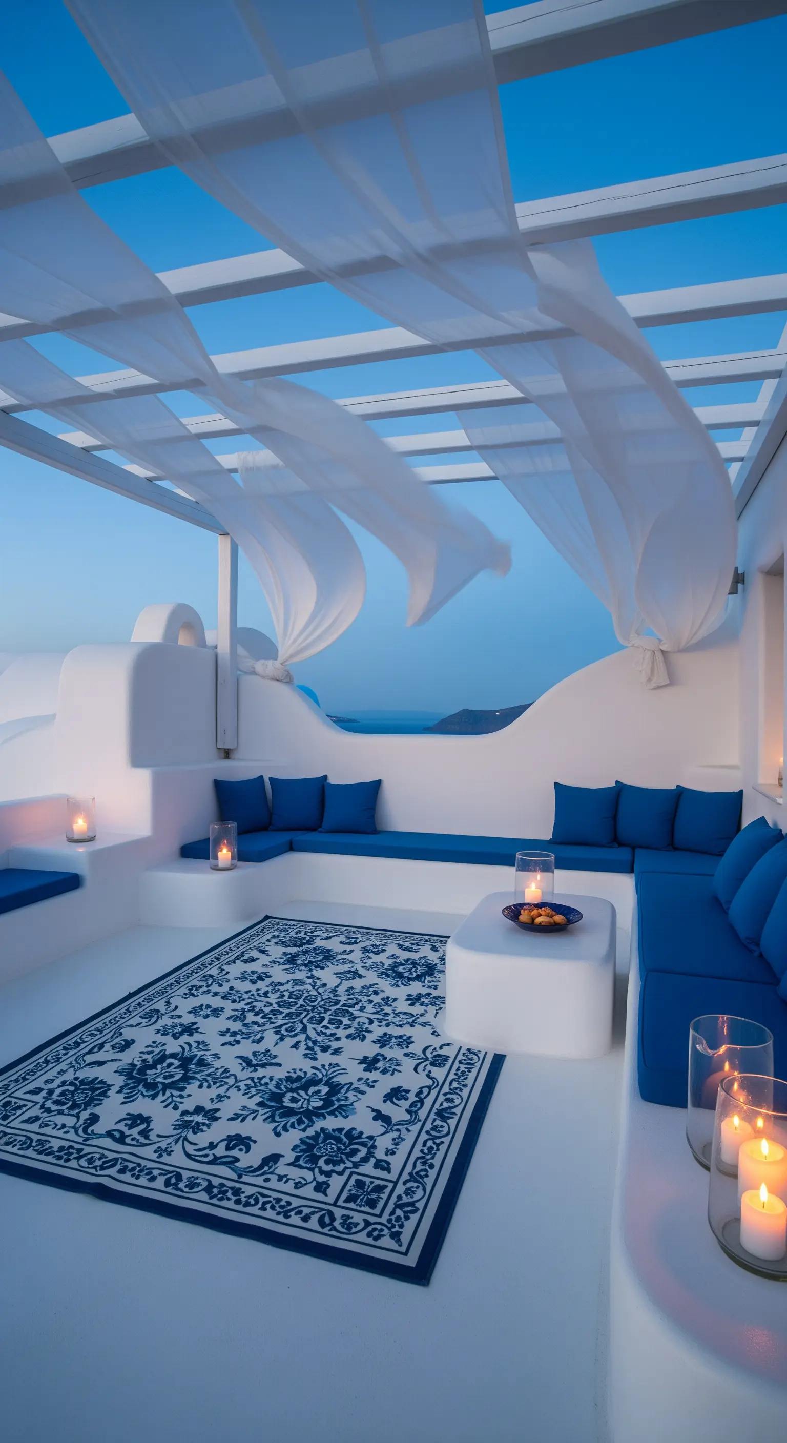 Terrazza bianca in stile Santorini con divani blu, tappeto grafico e candele in vasi di vetro.