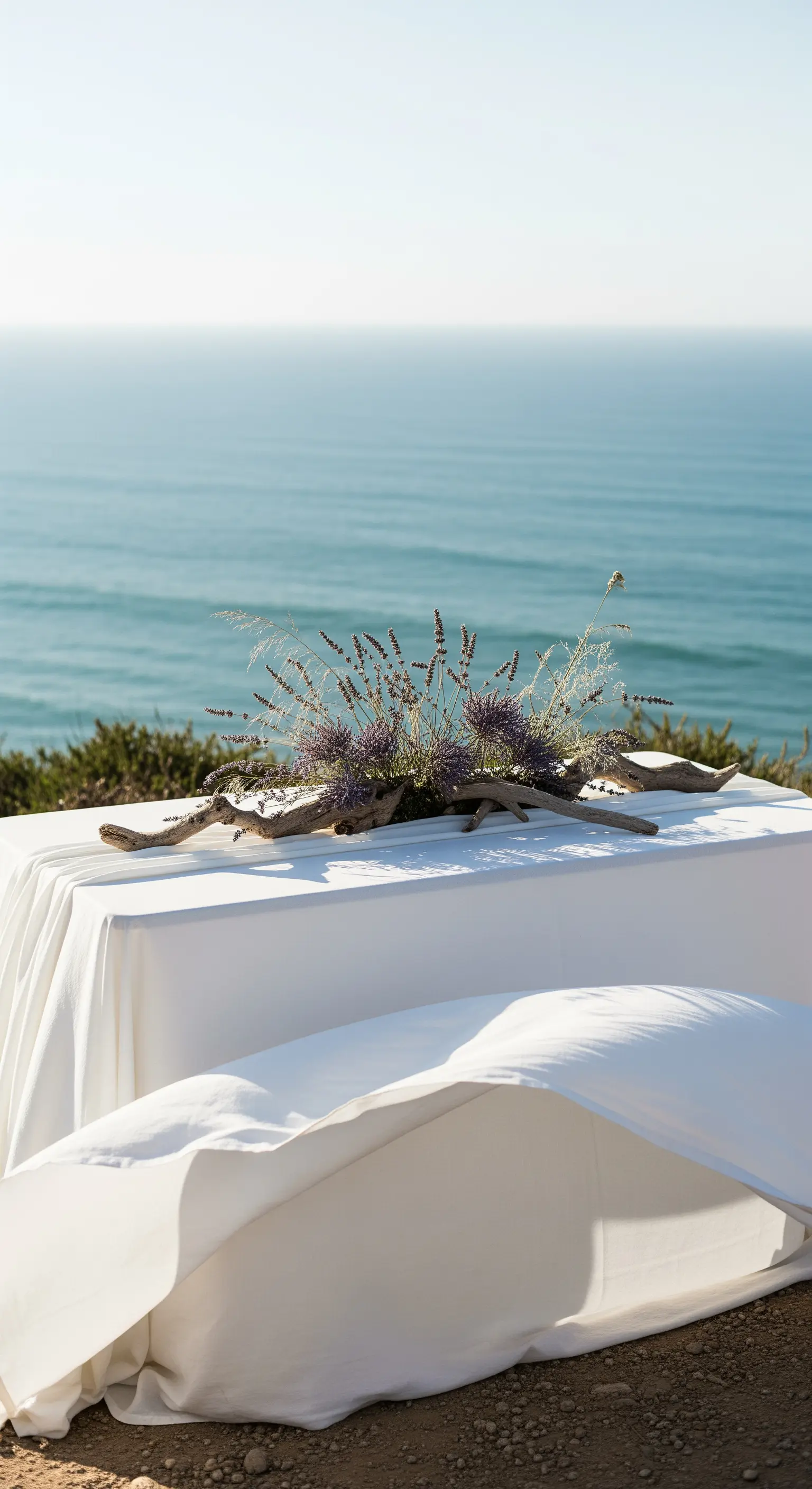 Tavolo con tovaglia bianca vista mare, decorato con legno e lavanda.