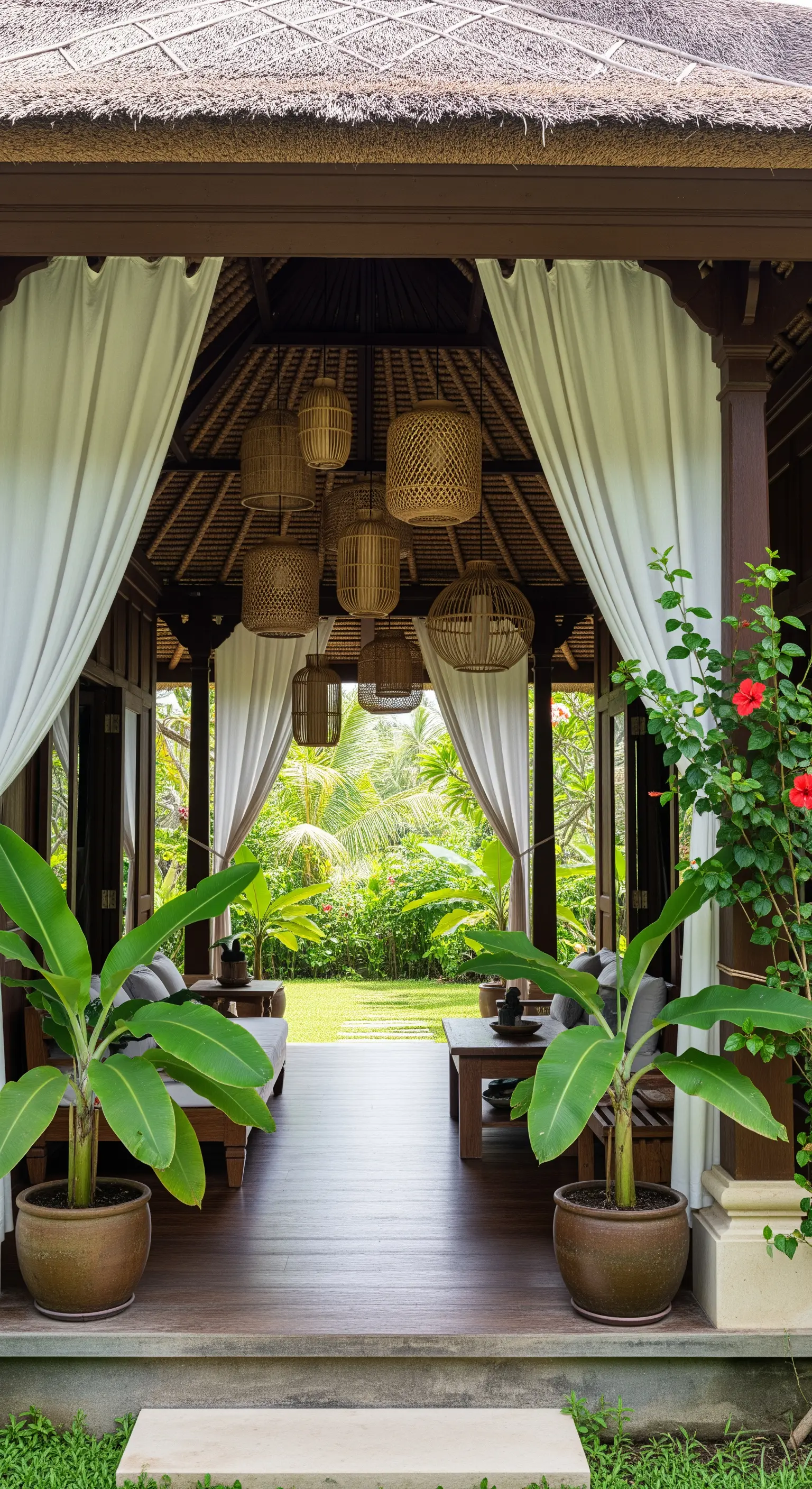 Padiglione in stile balinese aperto sul giardino, con lampadari in rattan.