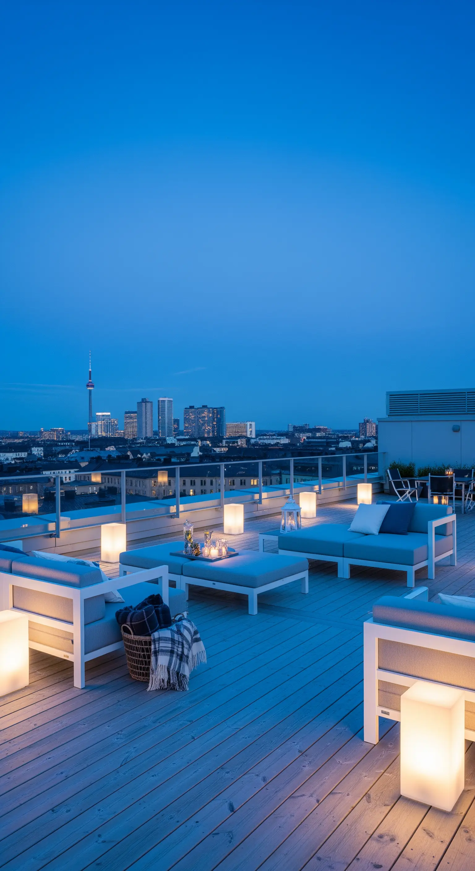 Terrazza panoramica con divani modulari, cubi luminosi e vista sulla città al crepuscolo.