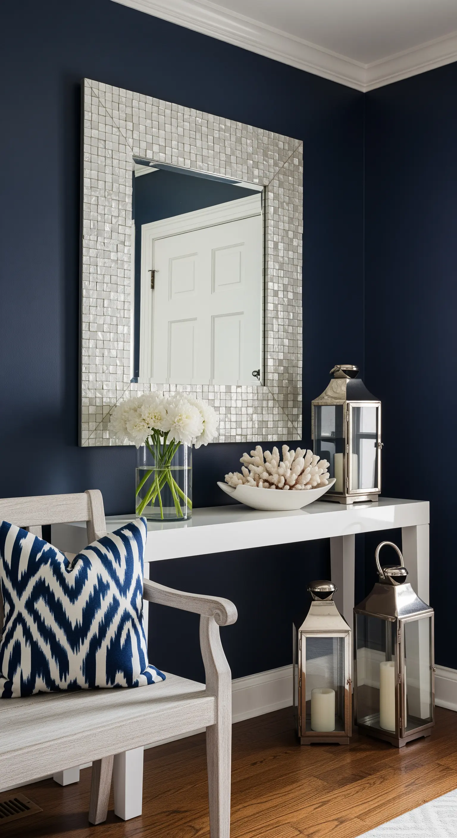 Ingresso elegante con pareti blu navy e consolle bianca con specchio in madreperla.
