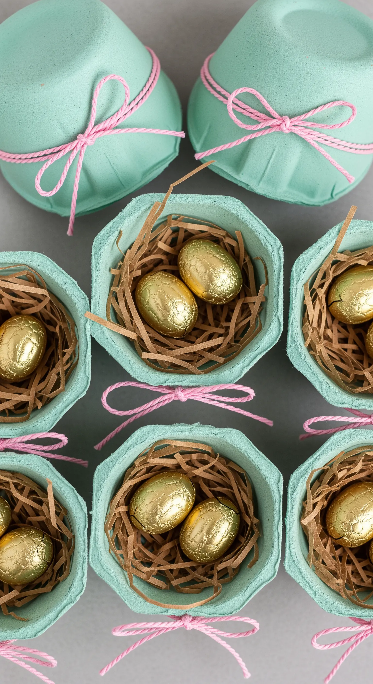 Portauova in cartone verde menta con paglia e ovetti di cioccolato dorati.