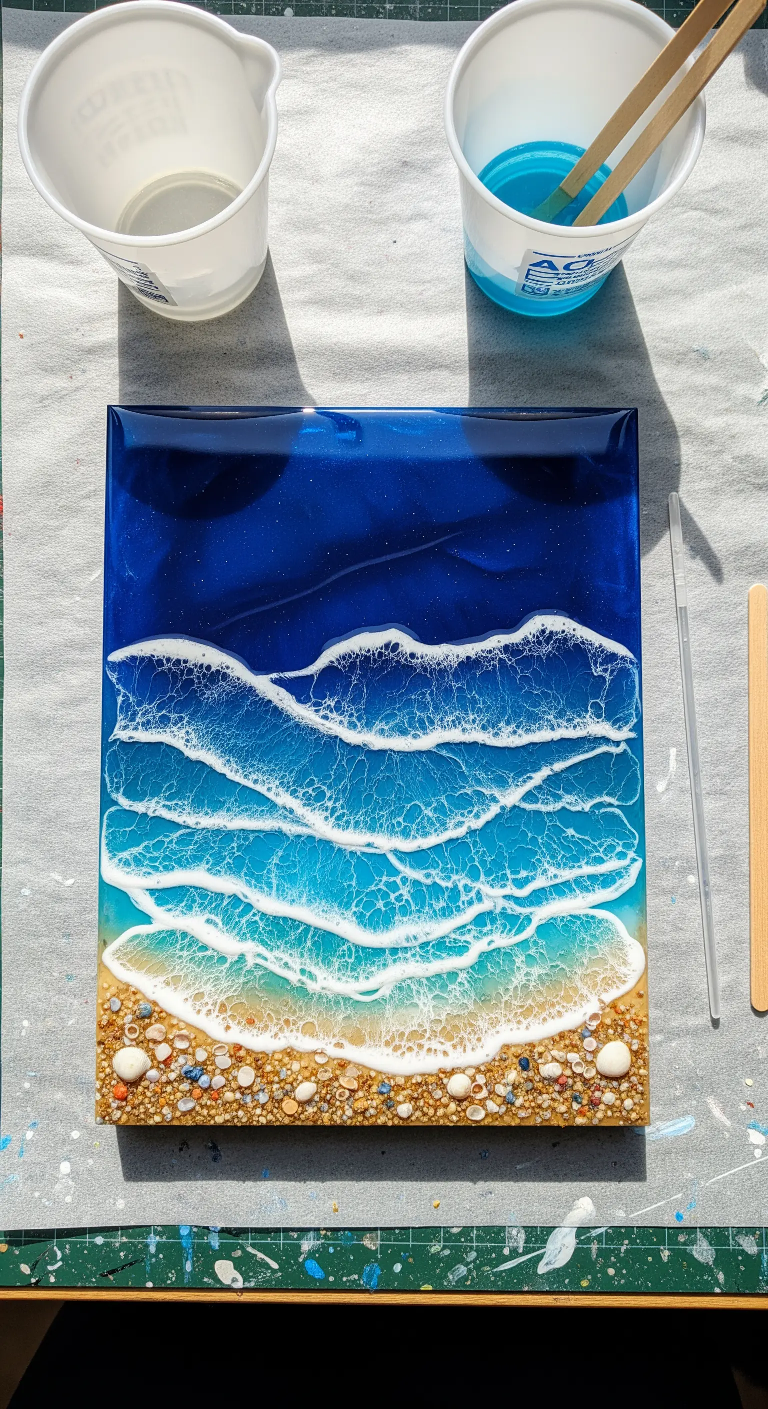 Quadro in resina che riproduce una spiaggia con onde, sabbia vera e conchiglie.