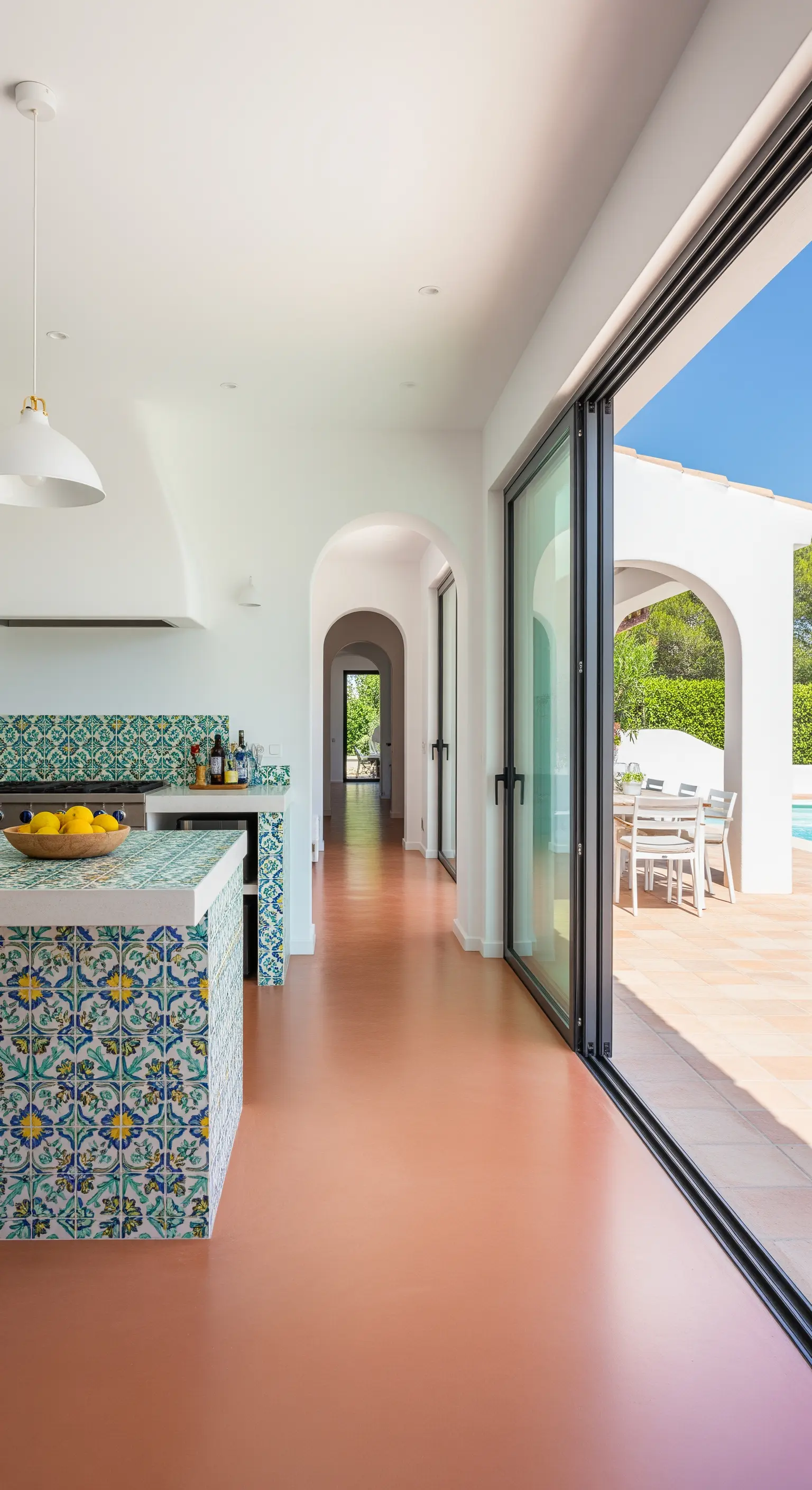 Cucina moderna con pavimento in resina color cotto che prosegue sulla terrazza esterna.