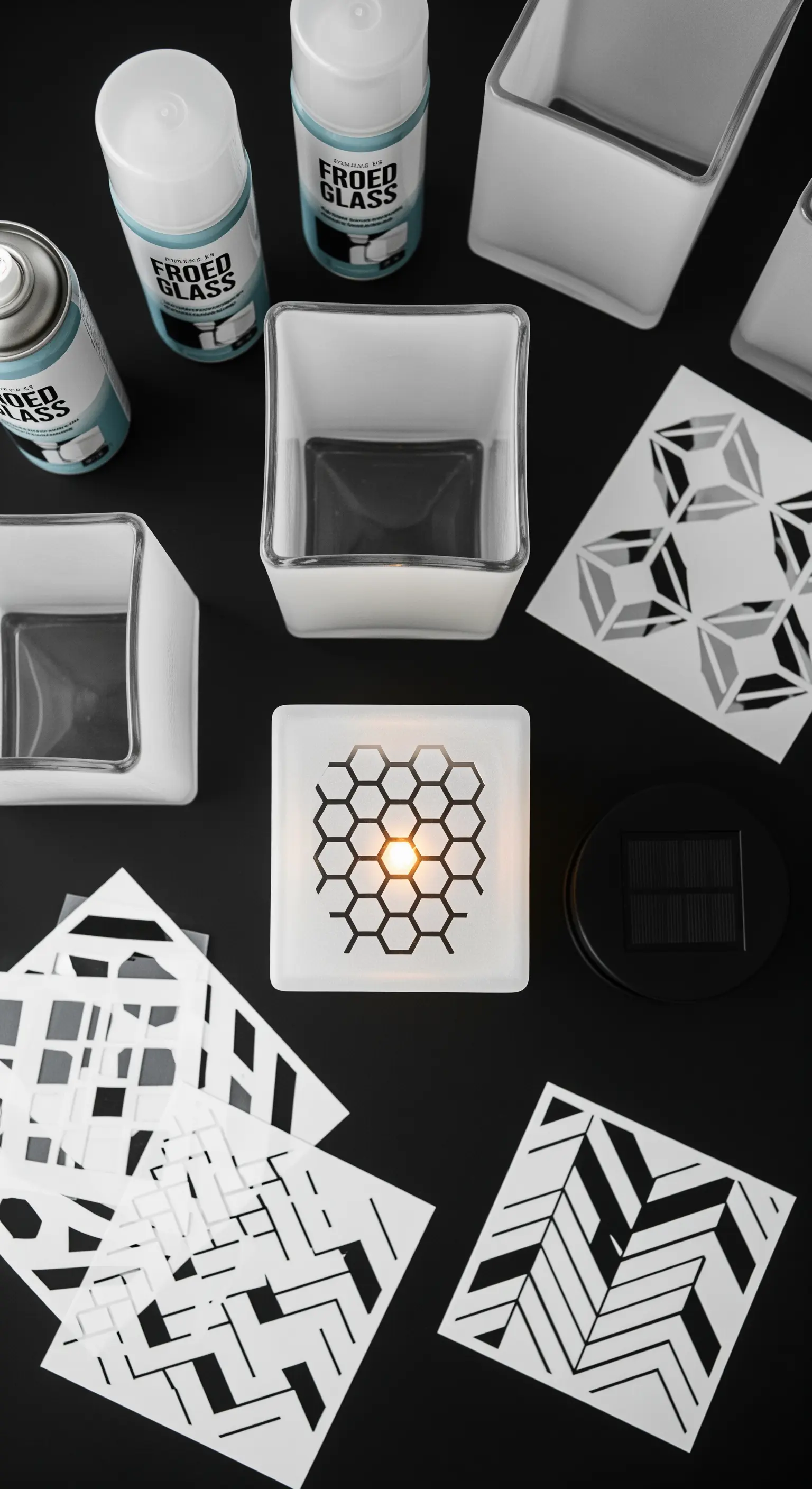 Contenitori in vetro smerigliato decorati con stencil geometrici, pronti per una luce solare.