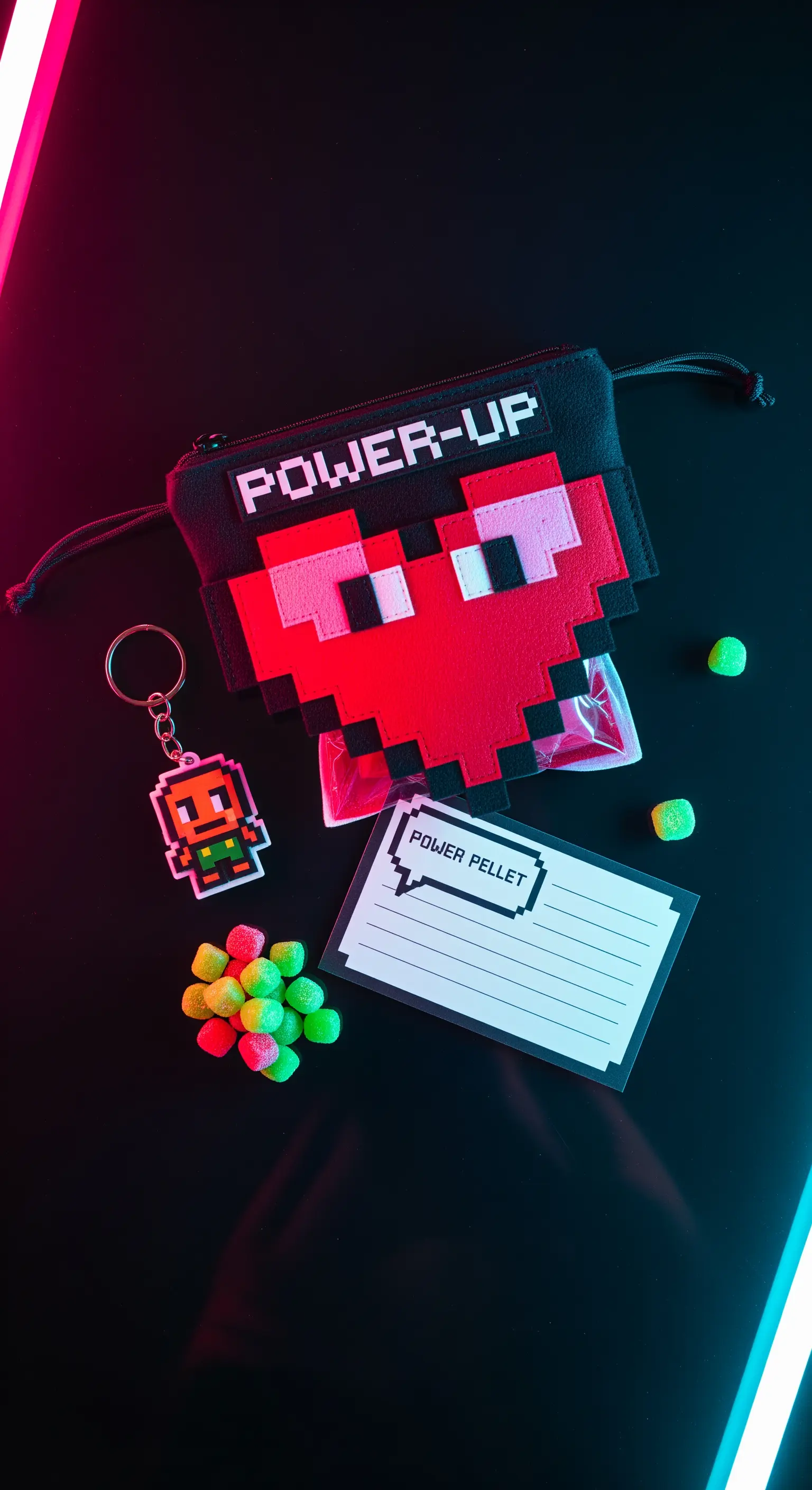 Pochette a tema retro-gaming con grafica pixelata, portachiavi a 8-bit e caramelle colorate.
