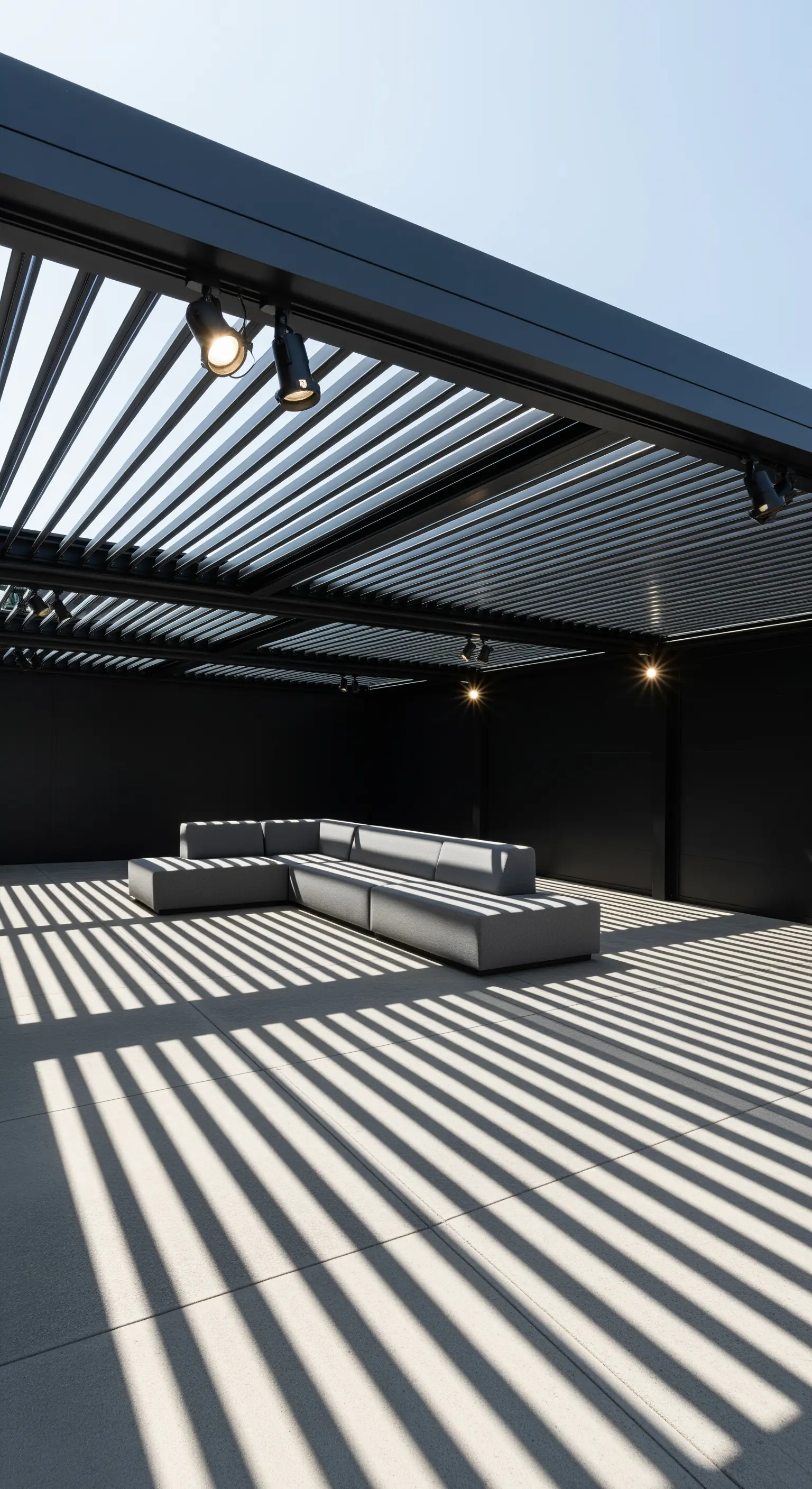 Patio coperto da una pergola a lamelle che proietta strisce di ombra nette su divani modulari grigi