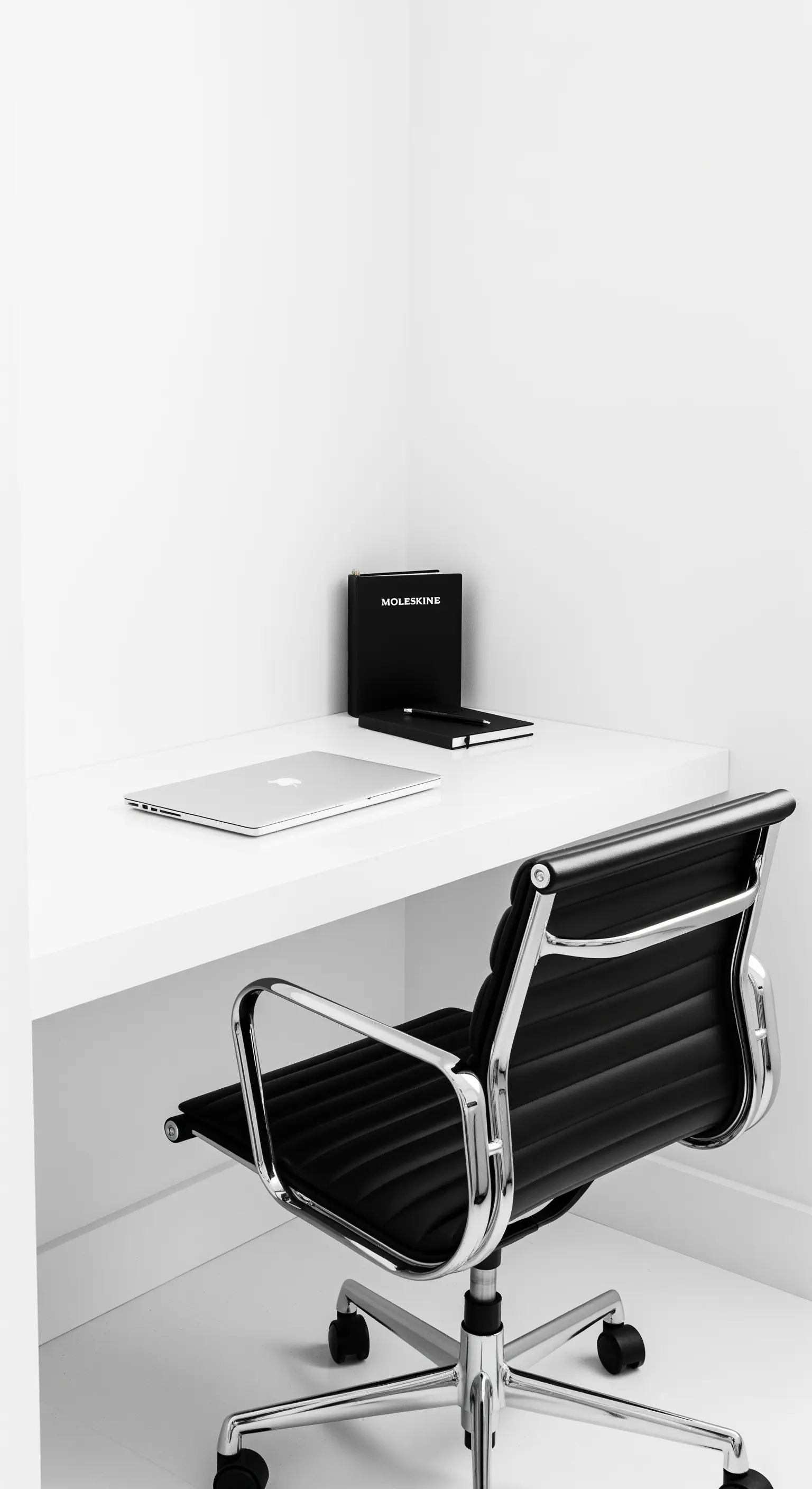 Scrivania bianca minimalista con sedia Eames nera e cromata in un ambiente total white.