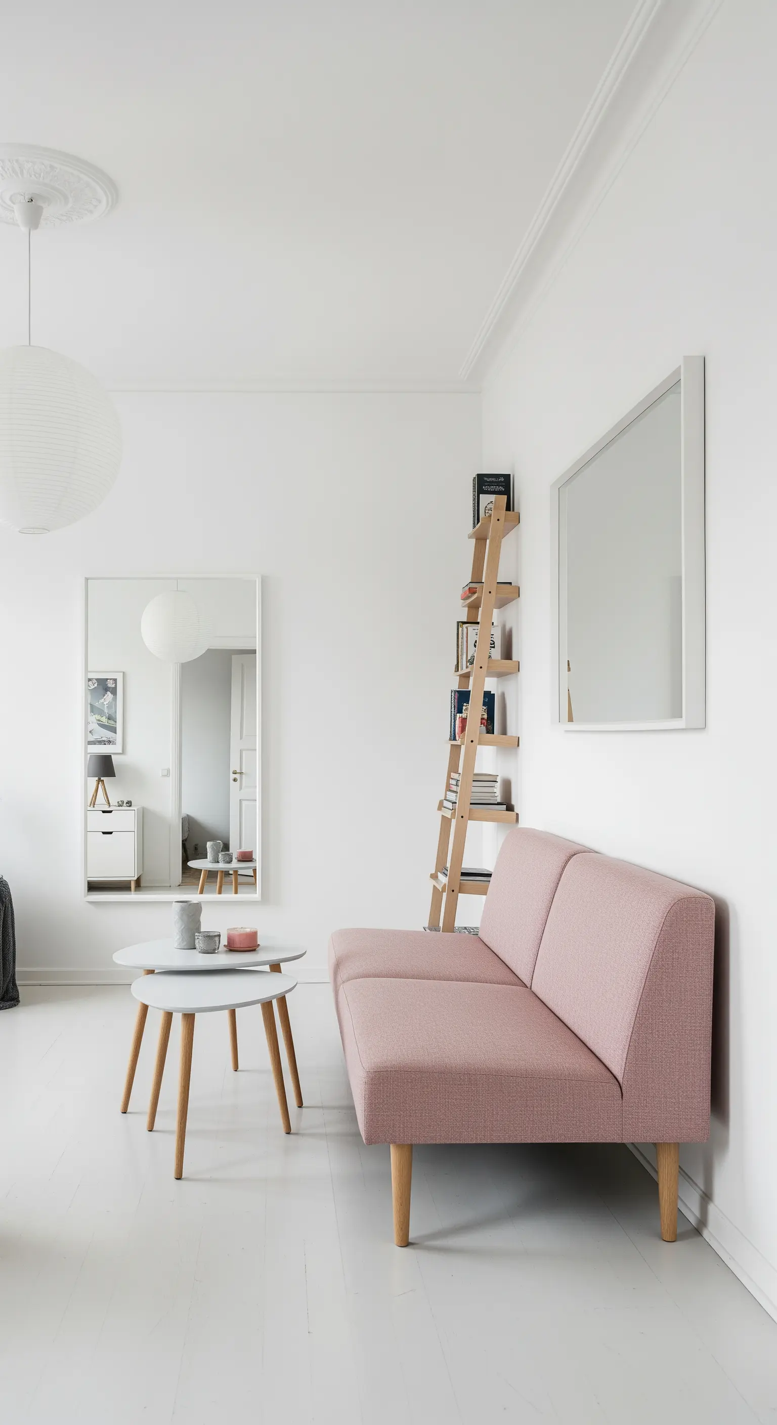 Soggiorno minimalista con divano rosa e tavolini con gambe sottili in legno chiaro