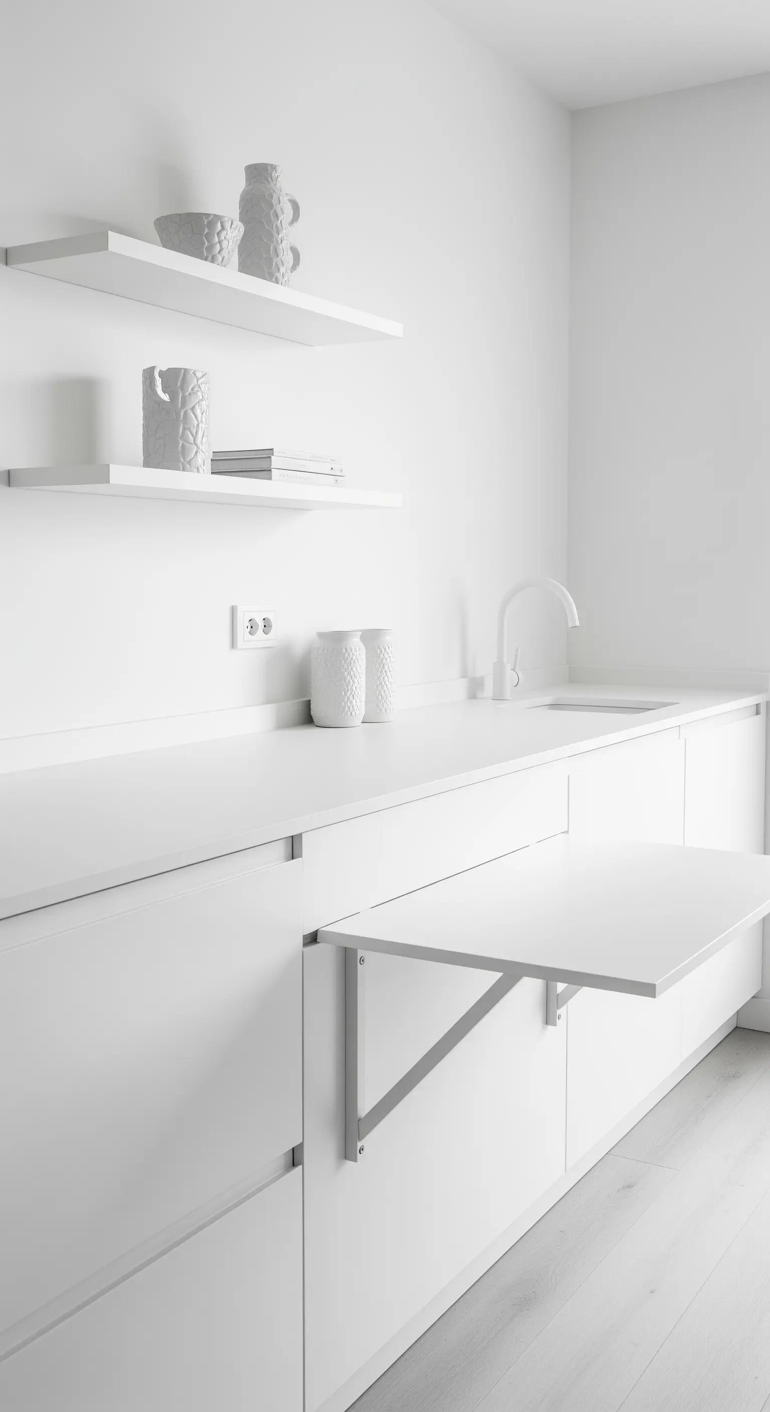 Cucina minimalista total white con tavolo a ribalta bianco e mensole fluttuanti.