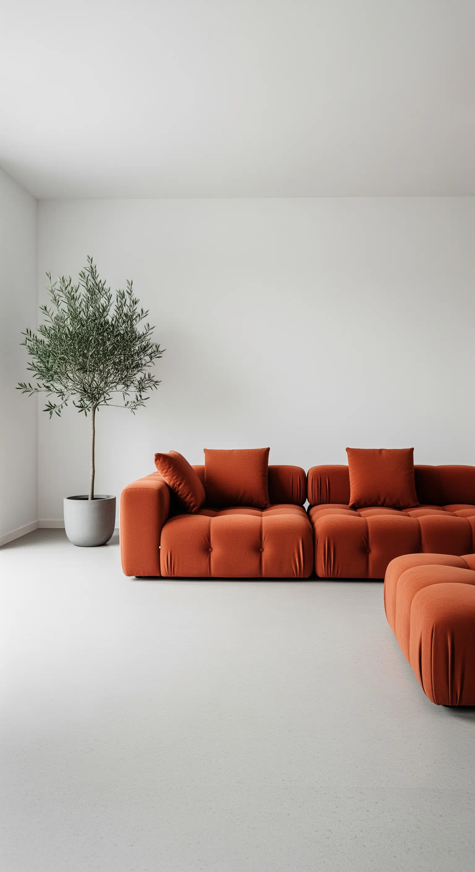 Divano modulare terracotta dal design scultoreo in un soggiorno bianco e minimalista