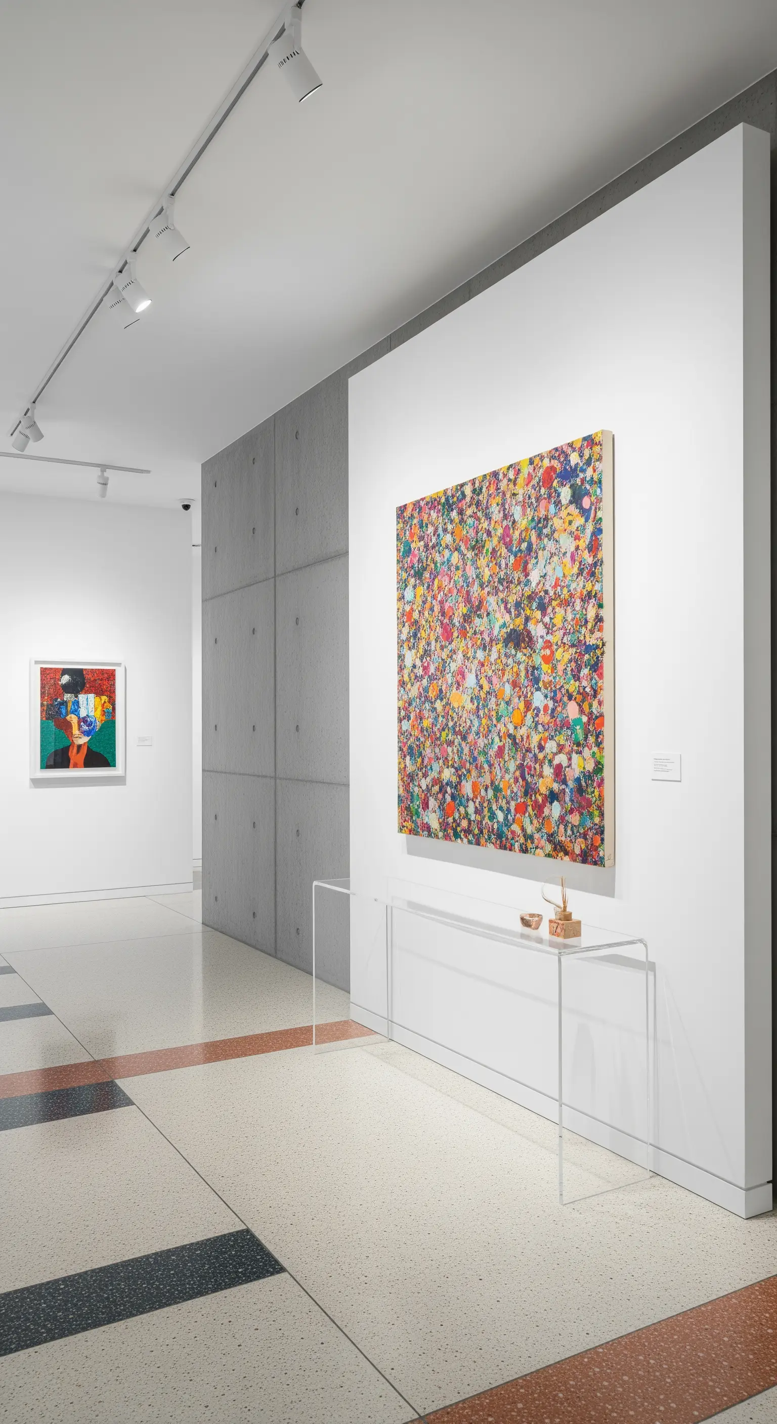 Ingresso stile galleria con parete in cemento, pavimento in terrazzo e una consolle trasparente.