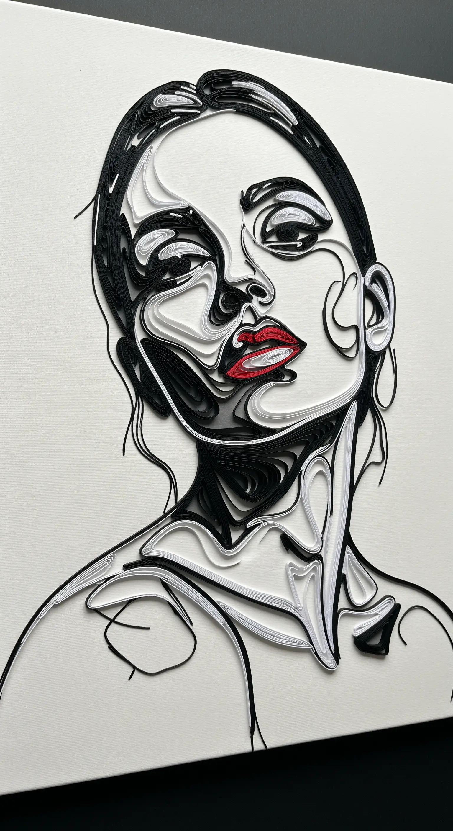Ritratto di un volto femminile realizzato con la tecnica del quilling in bianco e nero, con labbra rosse.