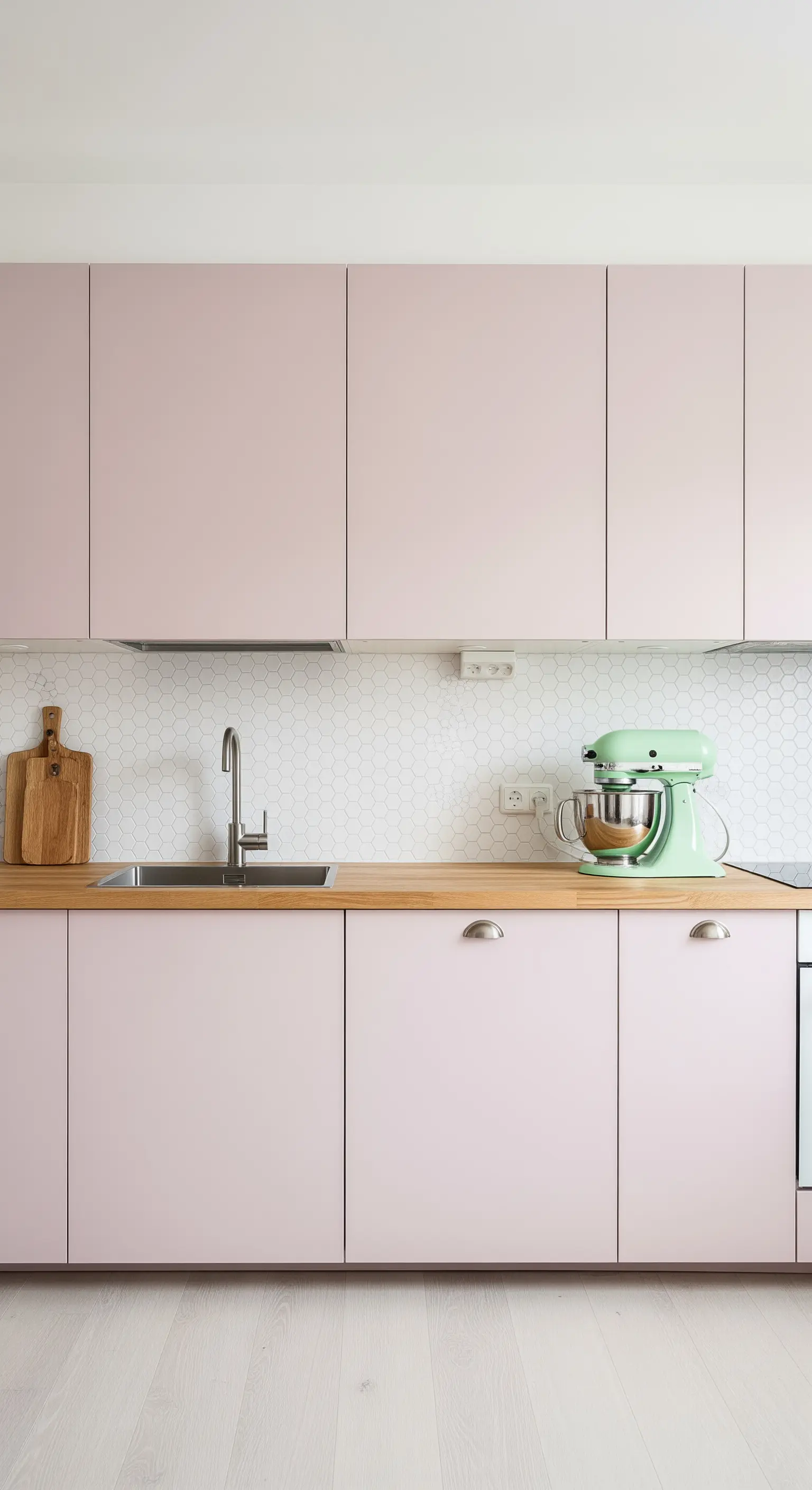 Cucina minimalista rosa con top in legno e impastatrice verde menta.
