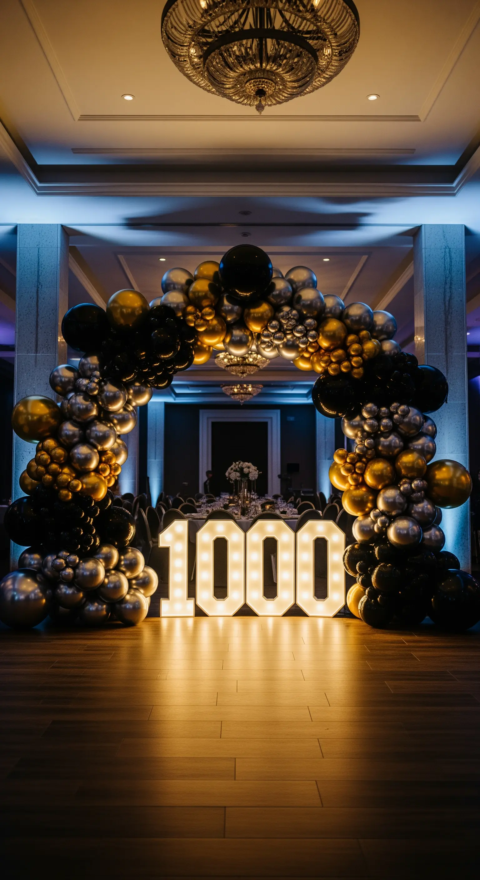 Imponente arco di palloncini neri, oro e argento che incornicia numeri luminosi in una sala elegante.