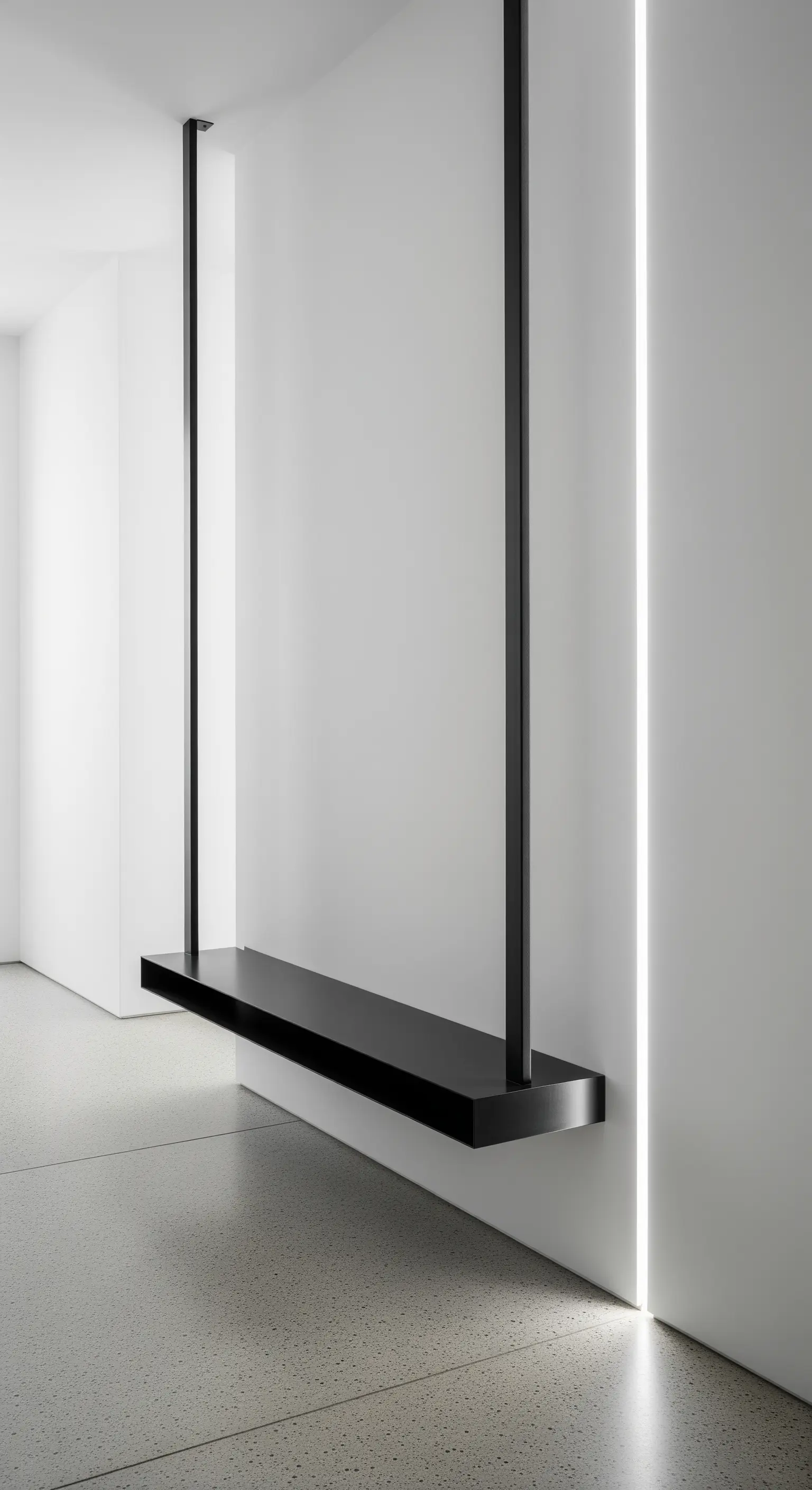 Mensola nera sospesa con tiranti verticali accanto a una linea di luce LED a parete.