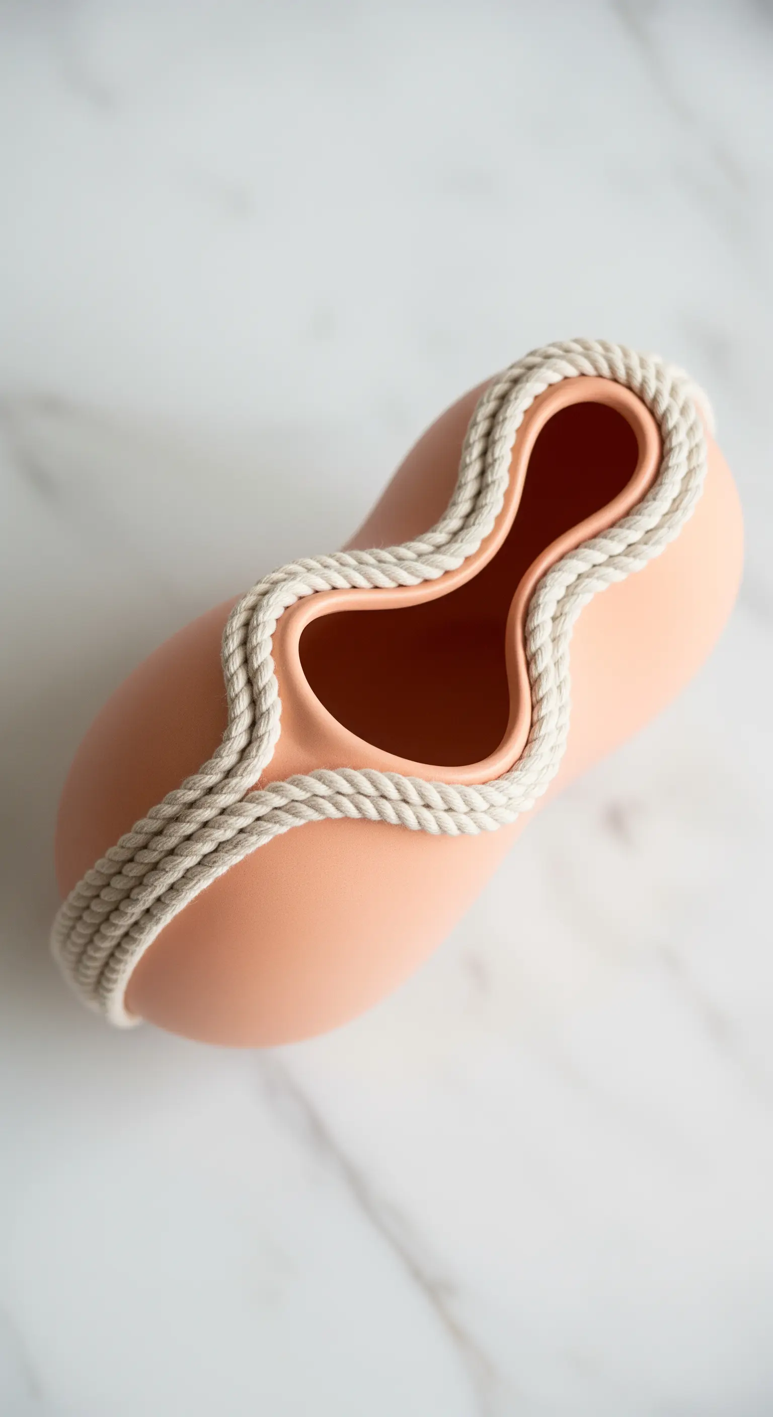 Vaso color terracotta dalla forma organica, con i bordi delineati da una corda bianca.