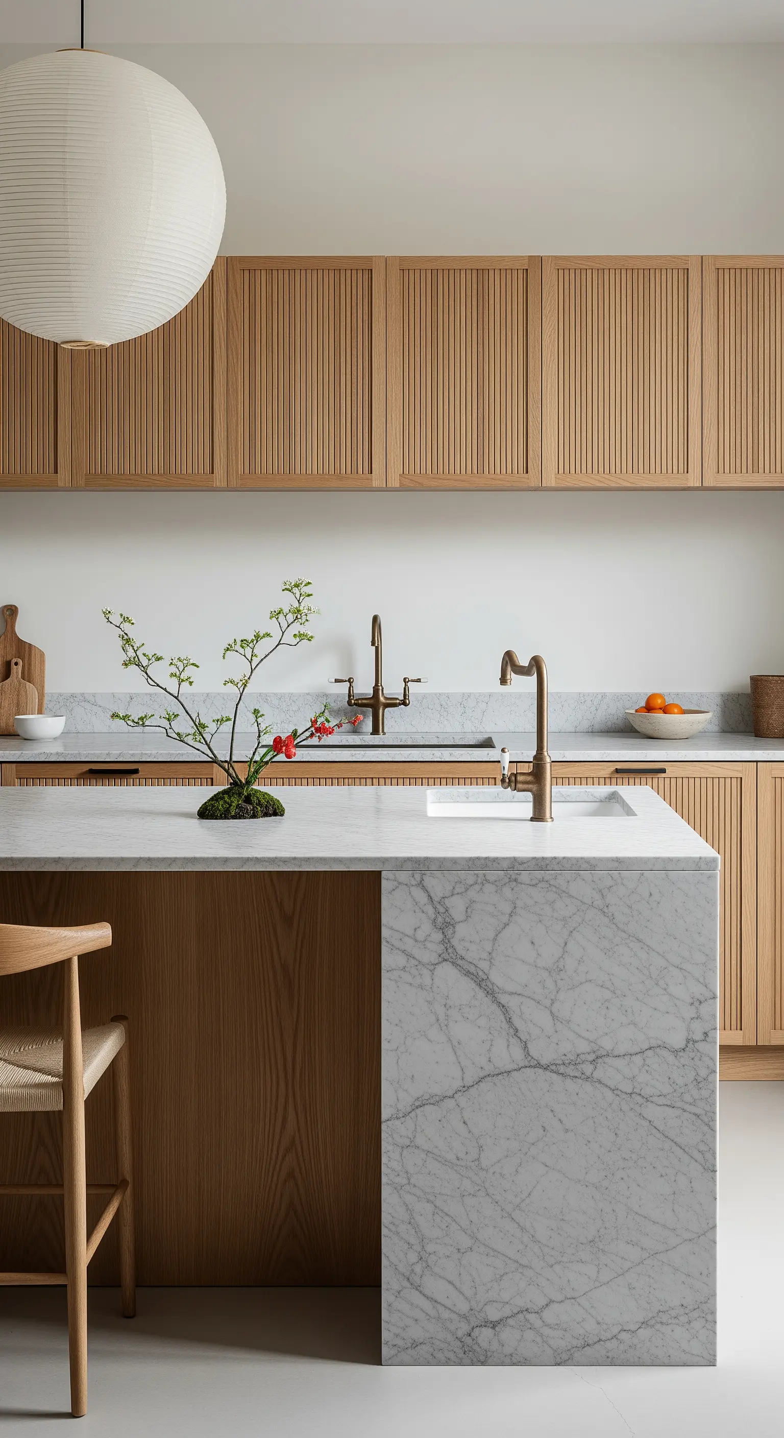 Cucina di ispirazione giapponese con mobili a listelli verticali e isola in marmo bianco.