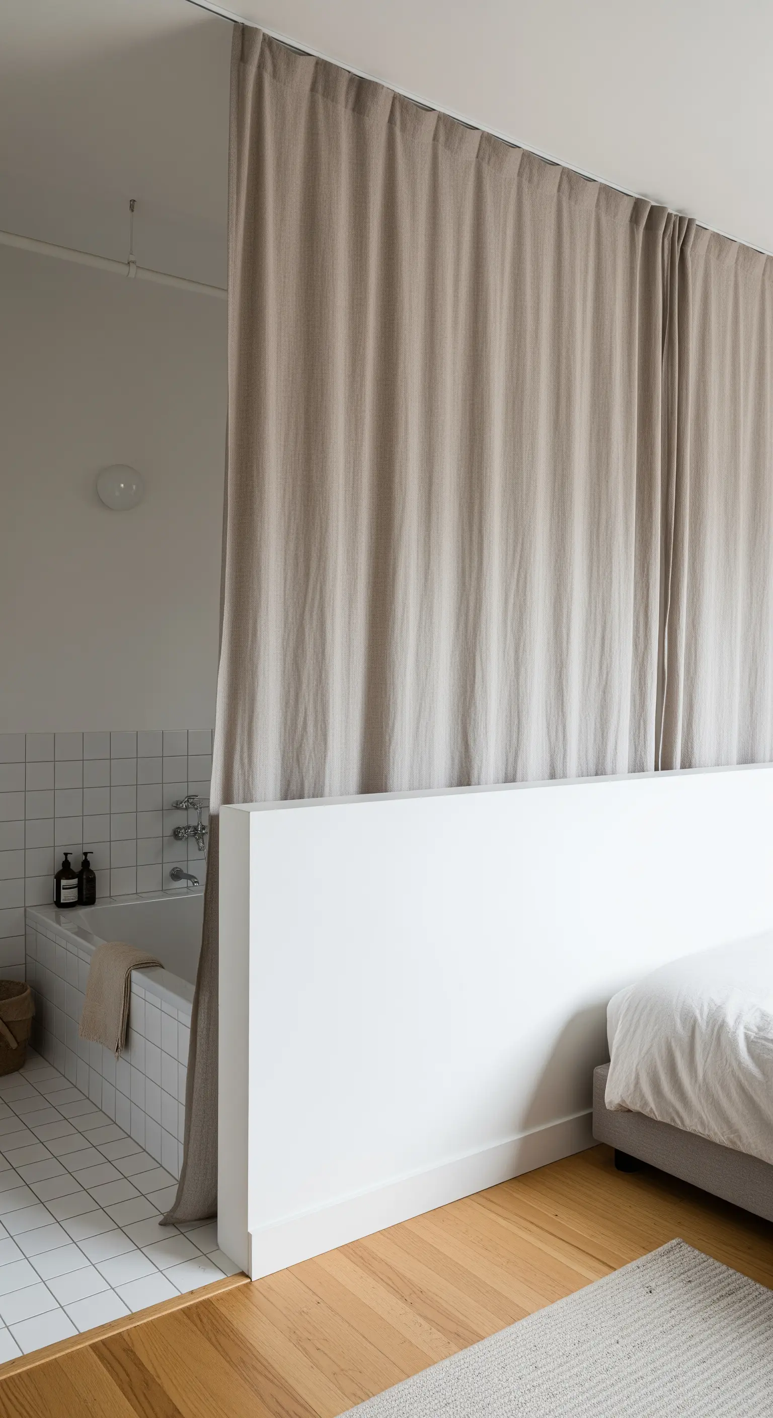 Bagno separato dalla camera da letto da un muretto bianco e una tenda in lino.