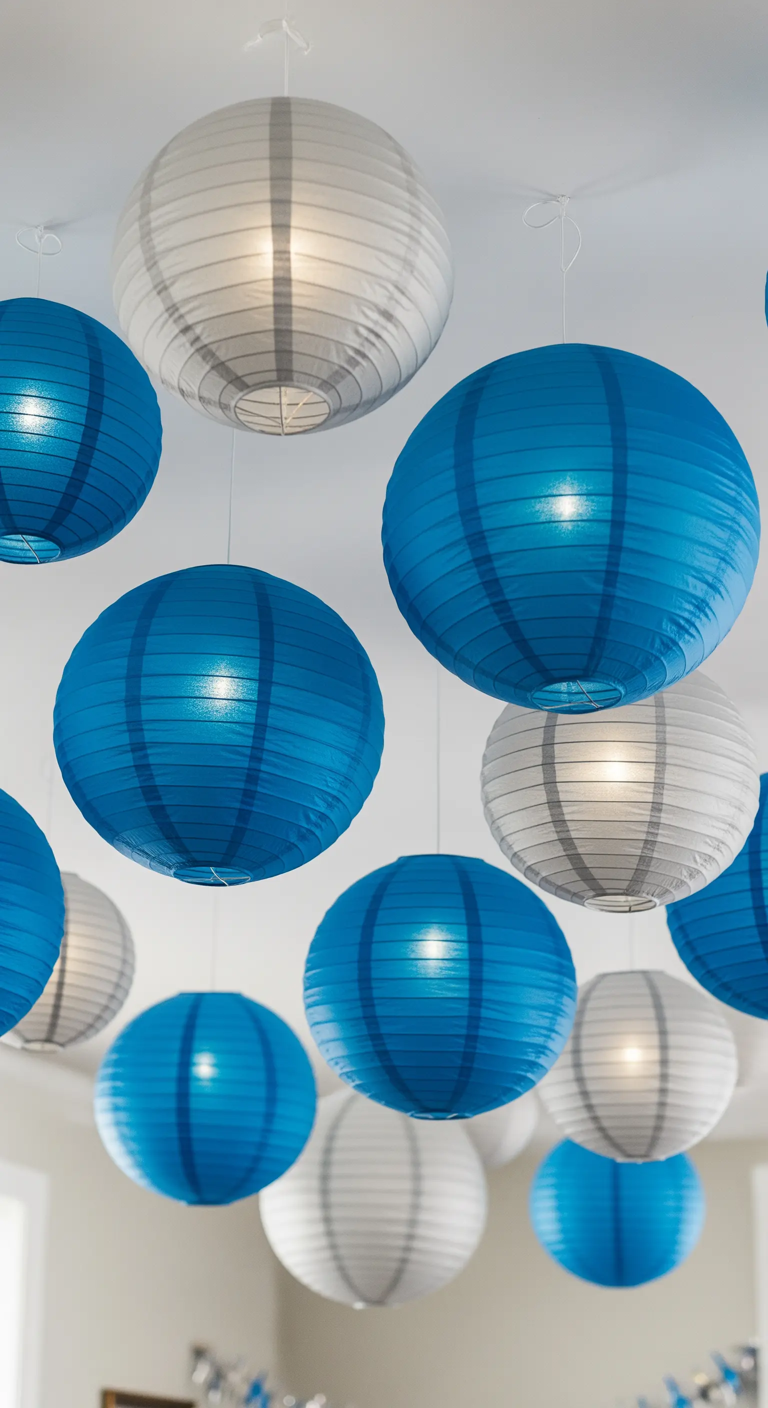 Soffitto decorato con lanterne di carta blu e bianche di diverse dimensioni, alcune illuminate dall'interno