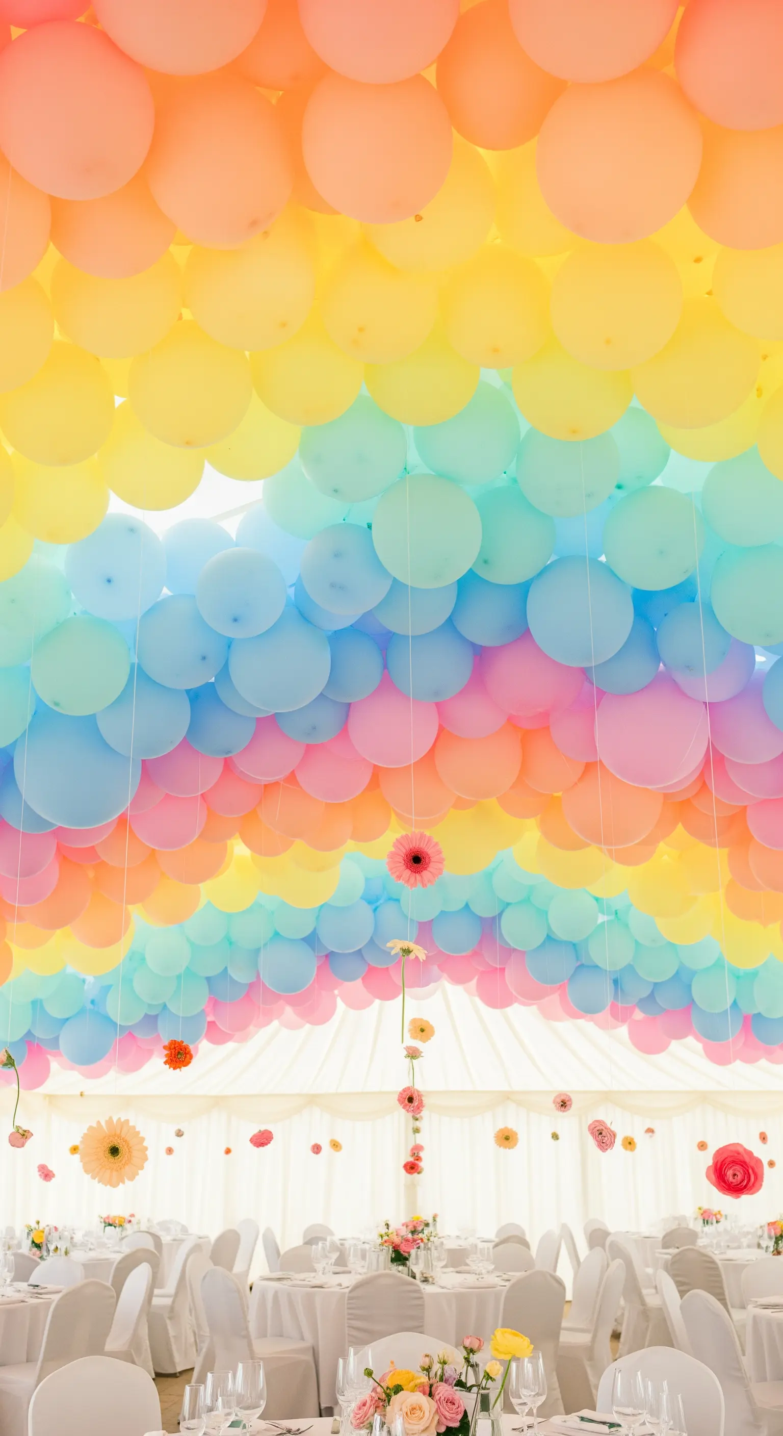 Soffitto di un tendone per feste coperto da file di palloncini in colori pastello.