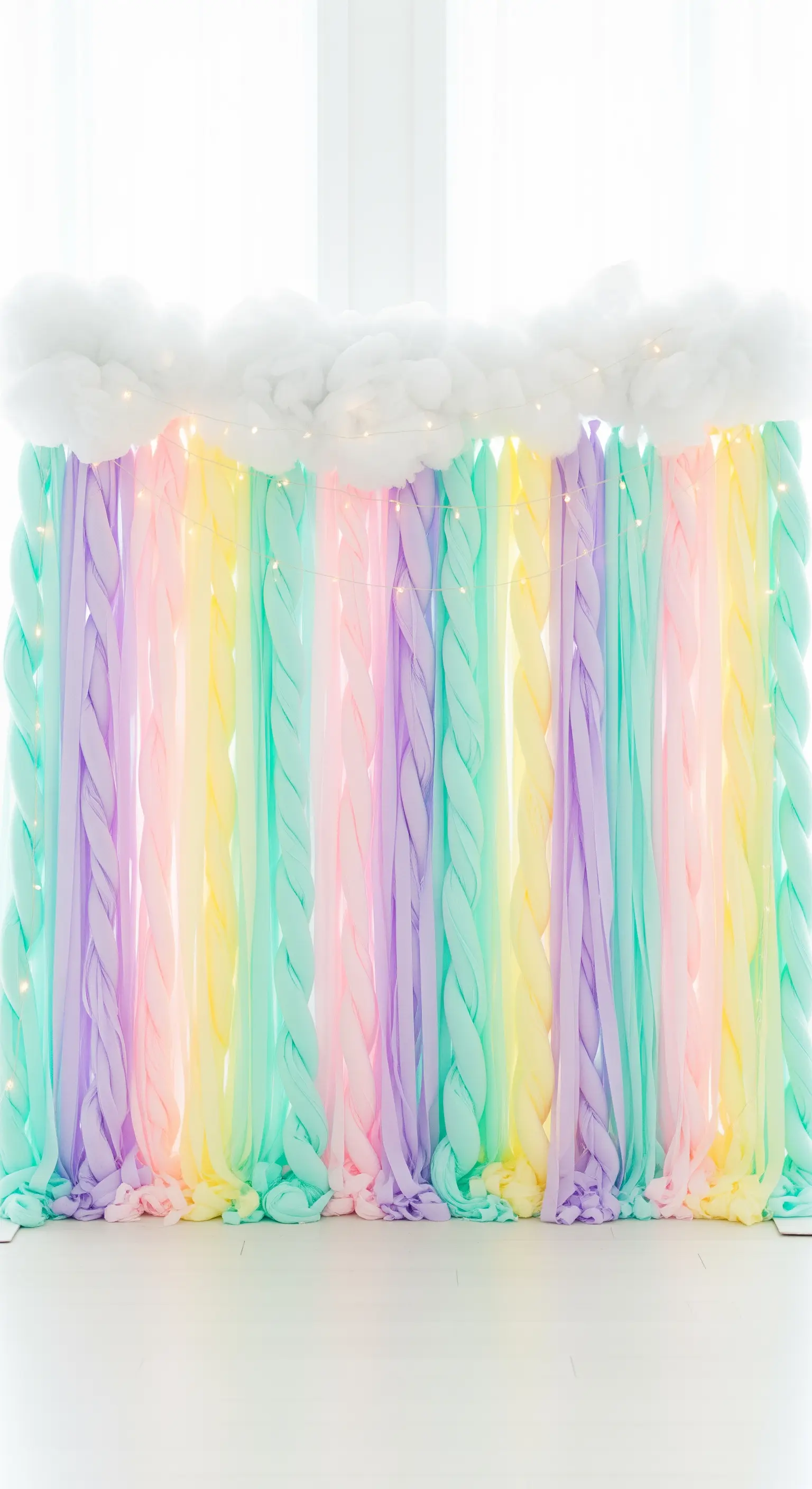 Tenda di carta crespa attorcigliata nei colori pastello, sormontata da nuvole di ovatta.