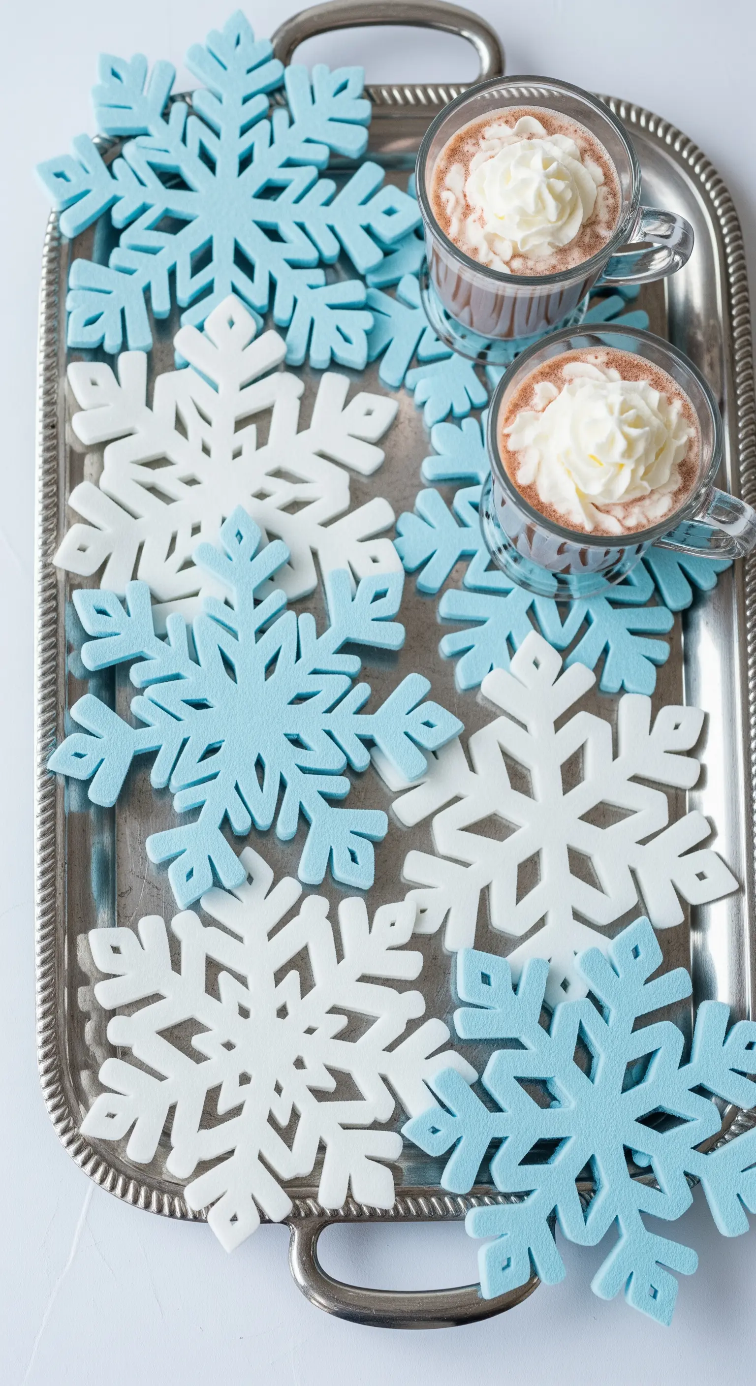 Sottobicchieri a forma di fiocco di neve bianchi e azzurri su un vassoio d'argento.