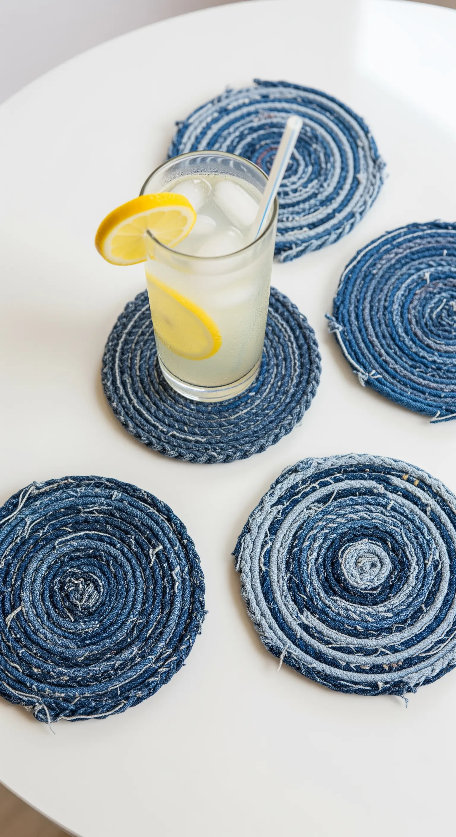 Sottobicchieri rotondi realizzati arrotolando e incollando strisce di tessuto di jeans riciclato.