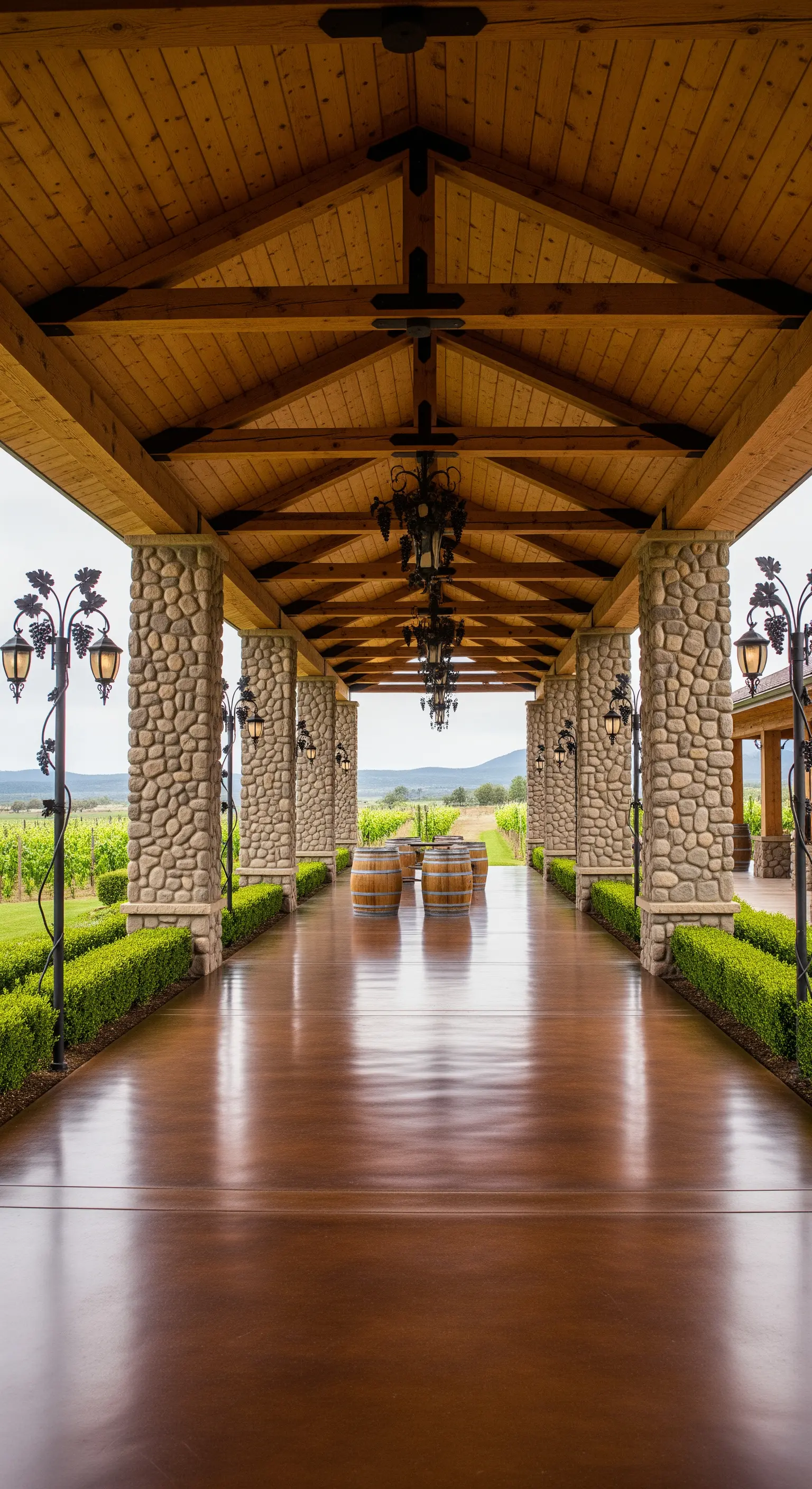 Lungo portico di una cantina con colonne in pietra, pavimento lucido e botti di legno.