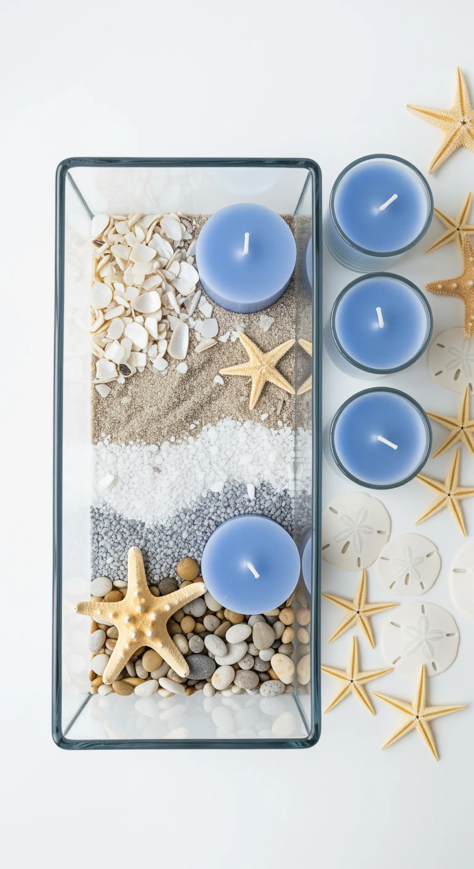 Vista dall'alto di un vaso rettangolare con strati di sabbia, sassi e conchiglie.