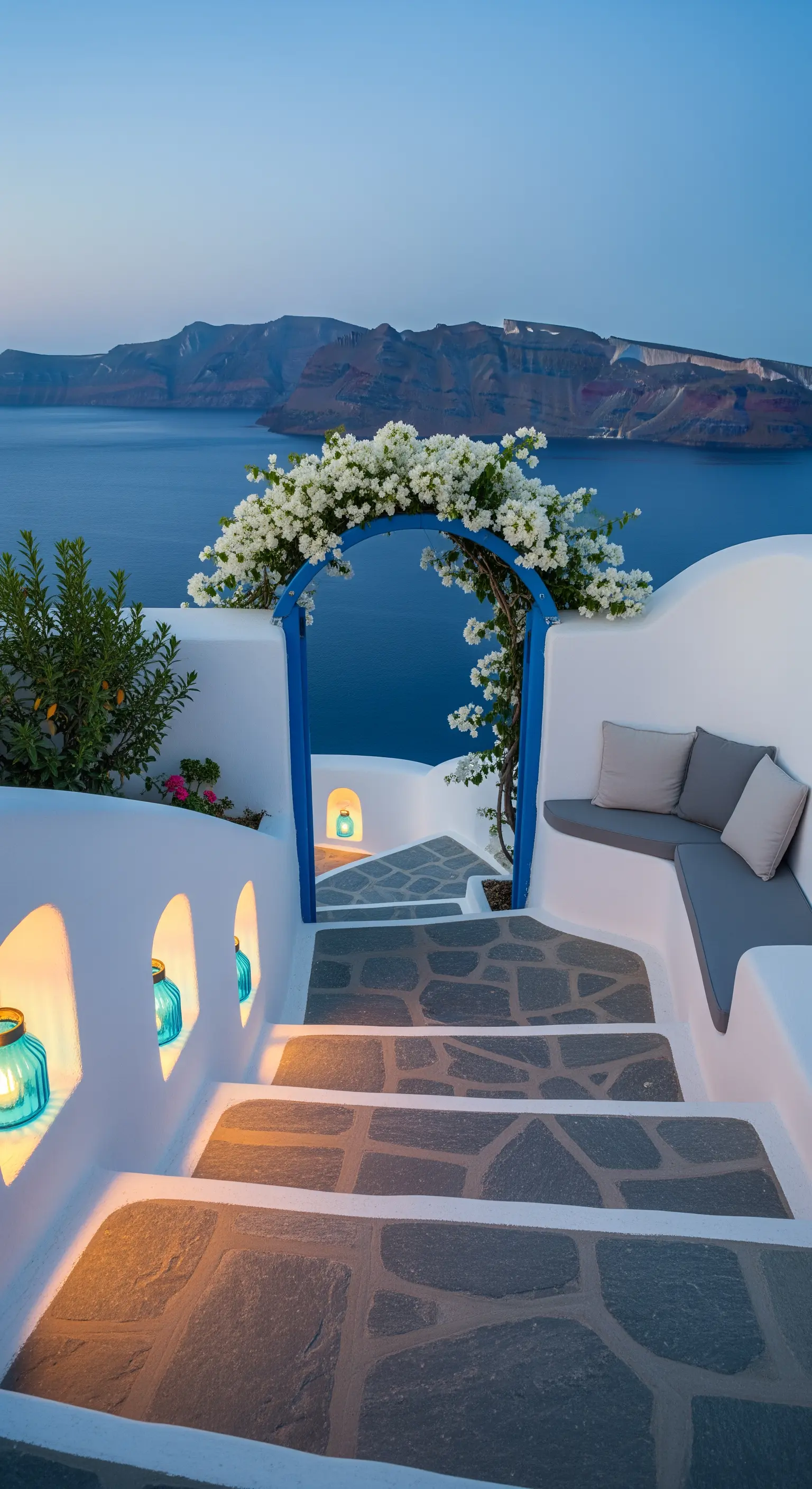 Terrazza in stile Santorini con pareti bianche, arco blu, bouganville e nicchie illuminate con lanterne