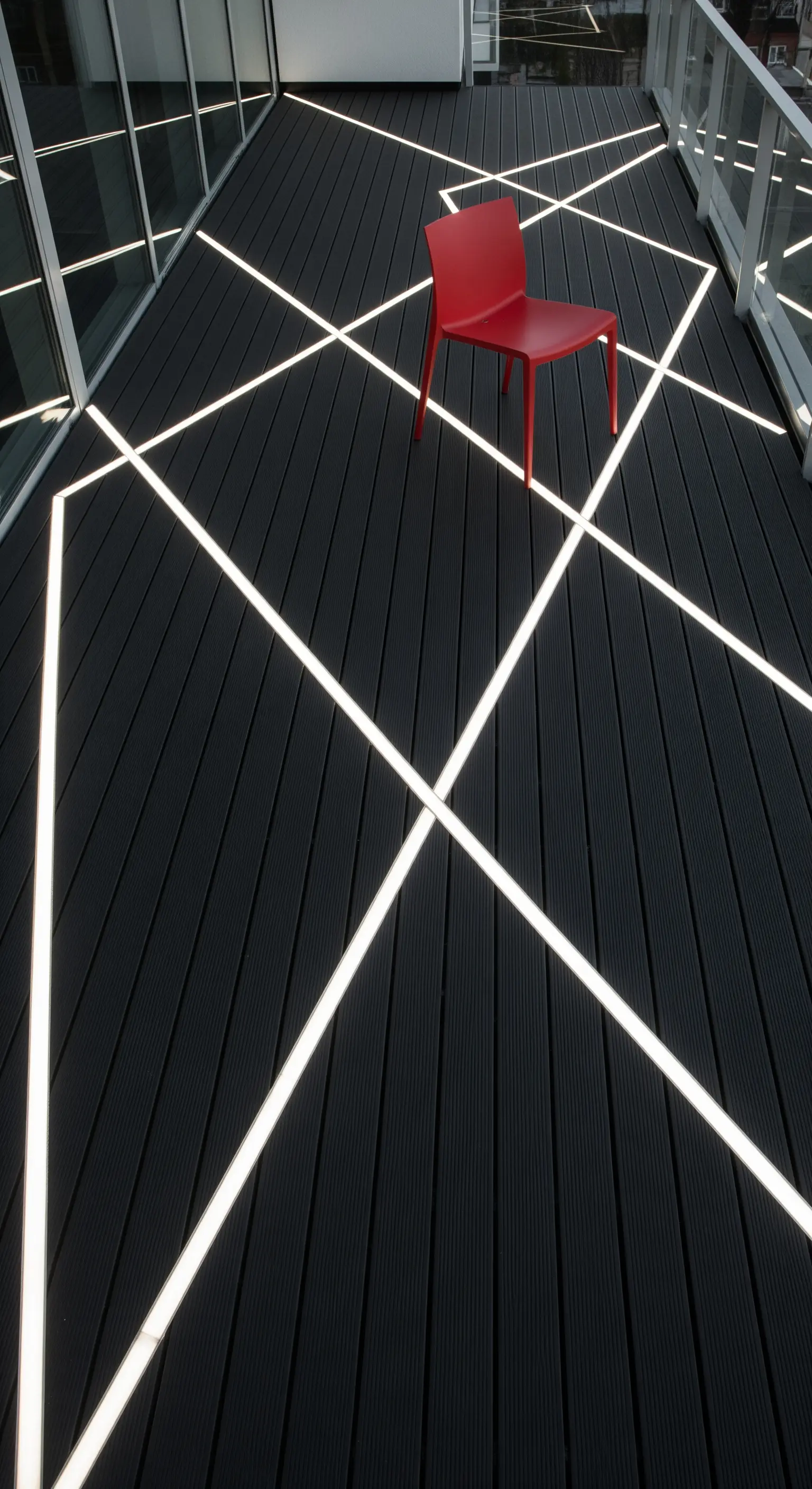 Pavimento in legno composito nero con linee di luce LED che creano un pattern geometrico astratto