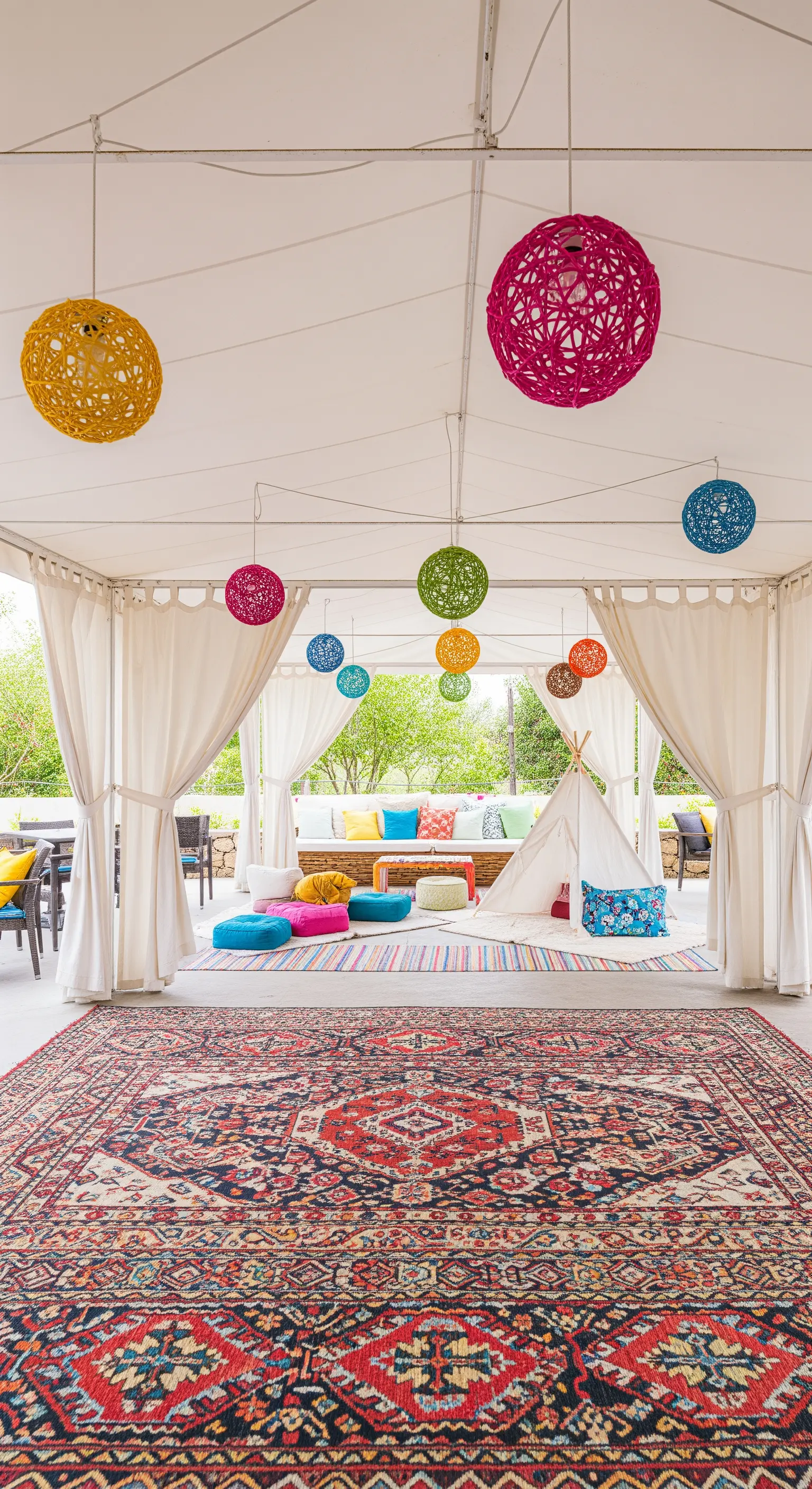 Patio coperto con teepee, cuscini colorati, lampade a sfera e un grande tappeto persiano.