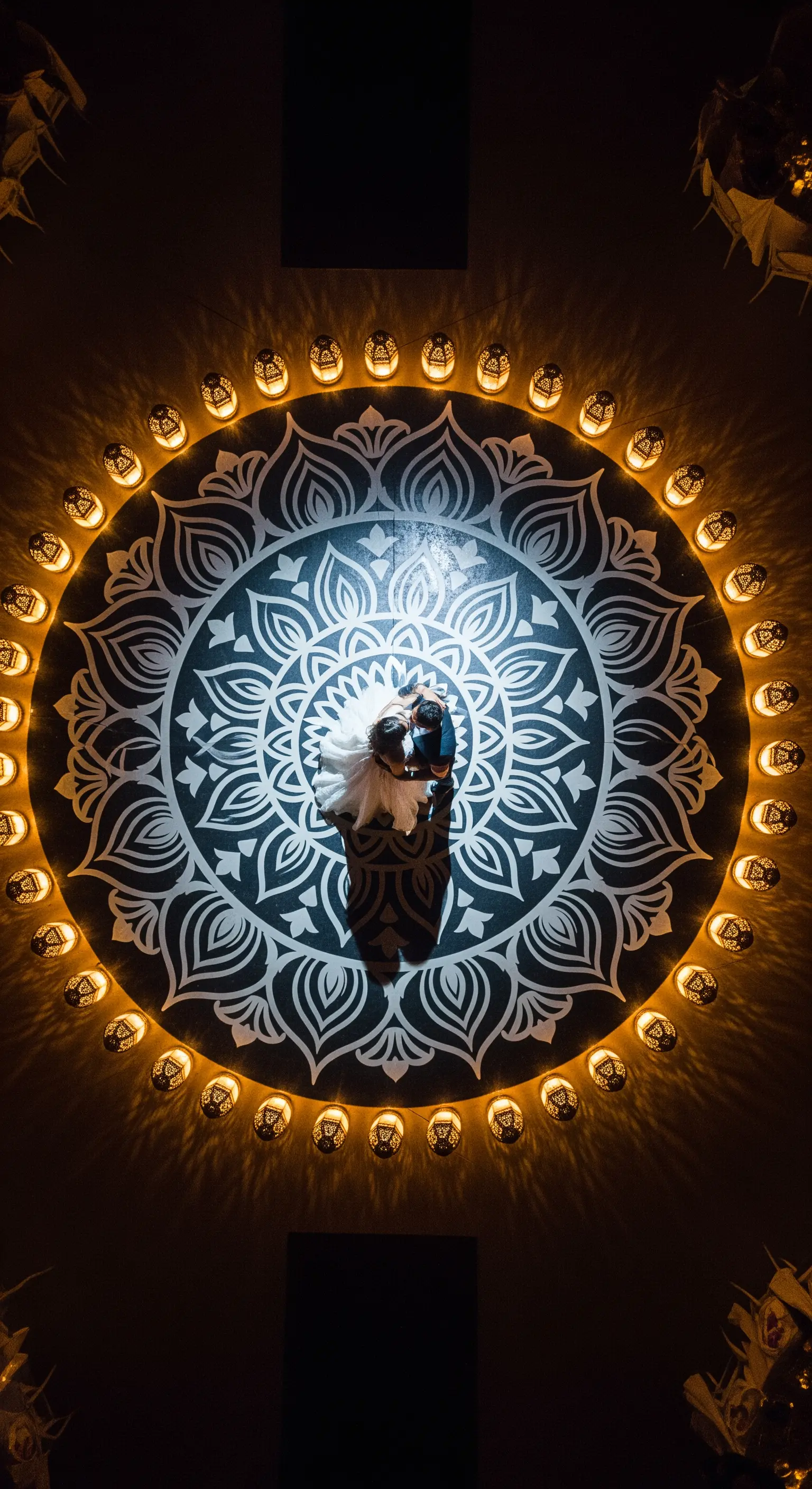 Vista dall'alto di una coppia di sposi che balla al centro di un grande mandala illuminato da lanterne