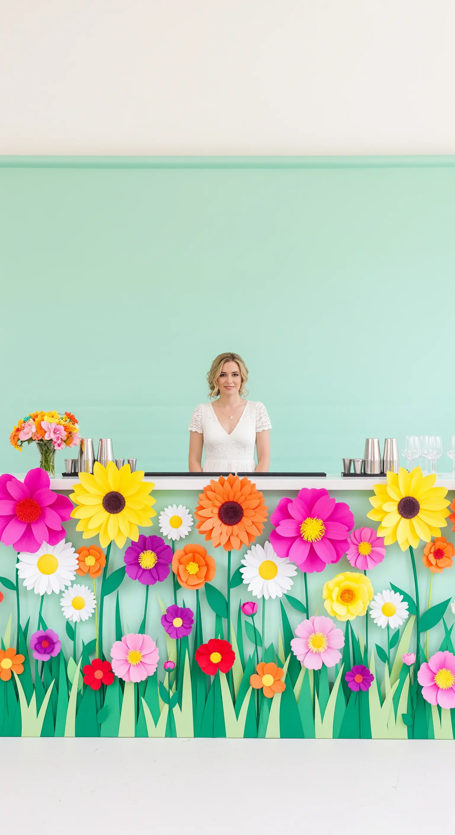 Bancone bar decorato con un prato di fiori di carta coloratissimi su sfondo verde menta.