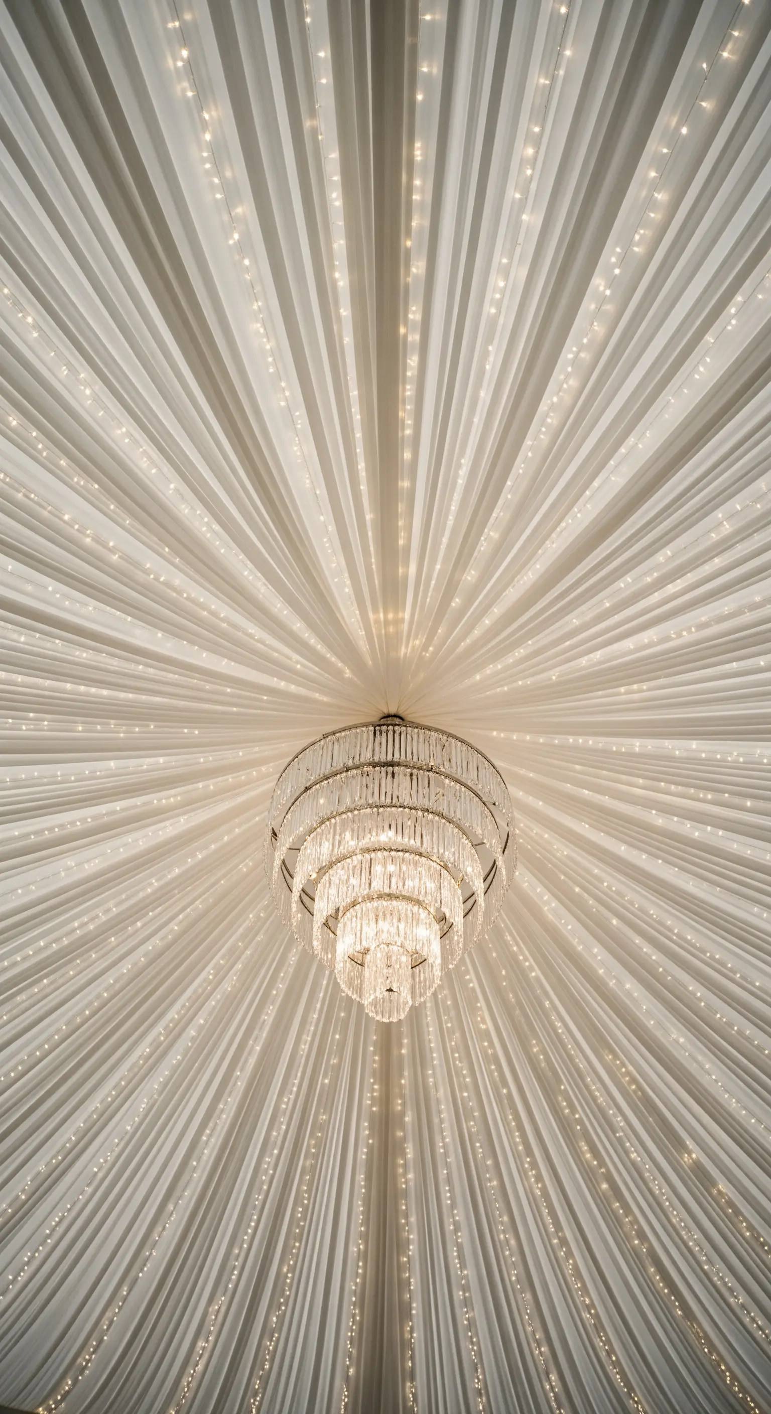 Soffitto di una tenda da ricevimento con un chandelier centrale da cui partono drappeggi a raggiera.