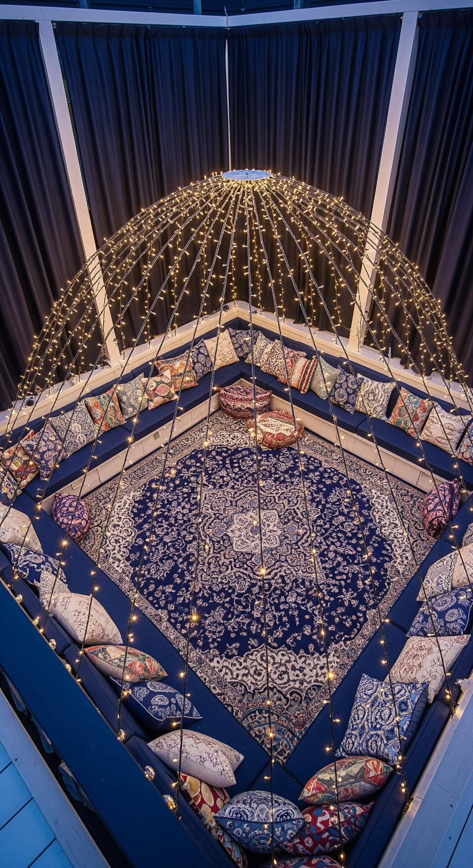 Struttura a cupola coperta di lucine, con un grande tappeto blu e cuscini etnici.