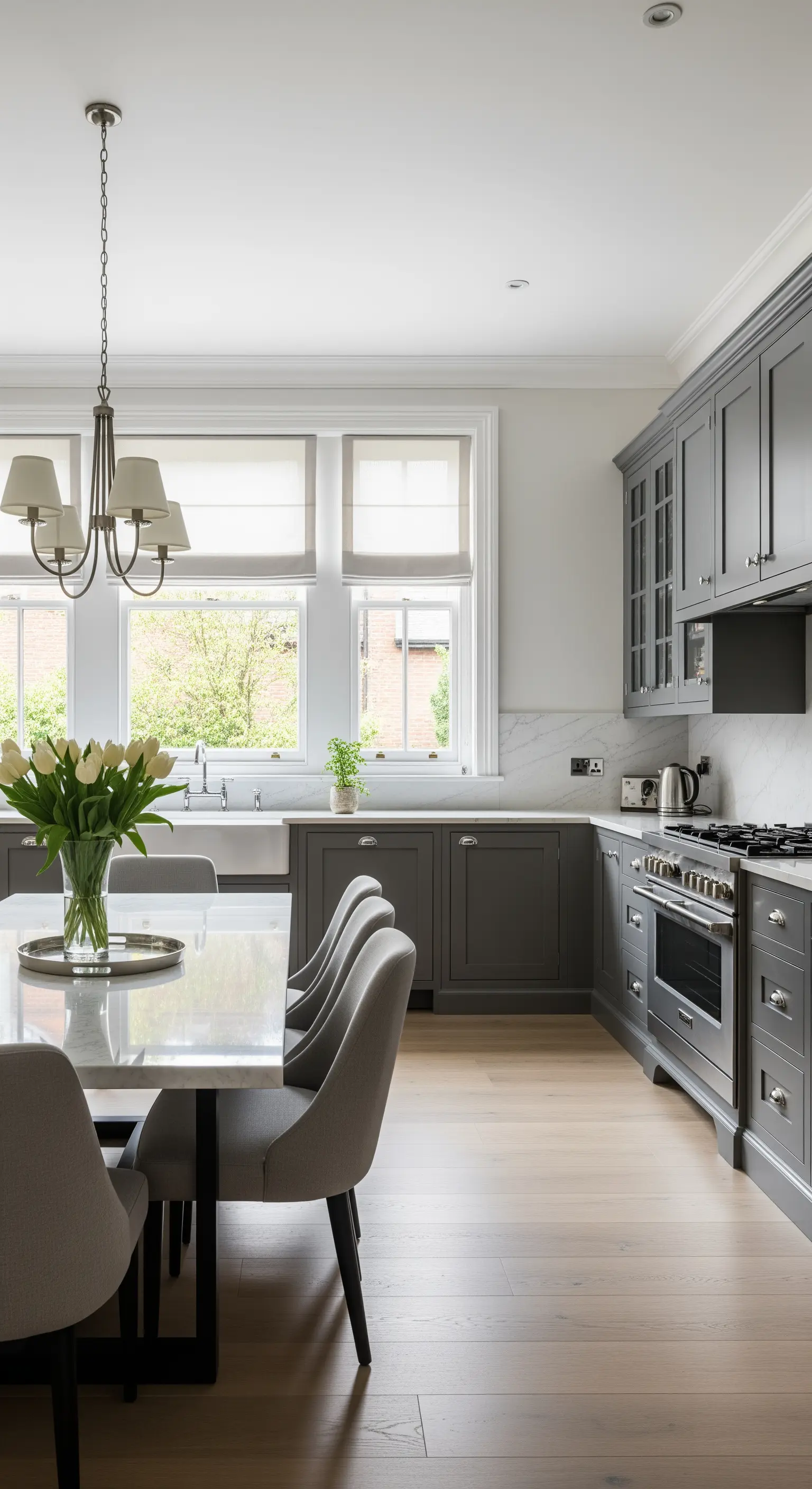 Cucina grigia elegante con tre finestre affiancate, ognuna con la sua tenda a pacchetto.